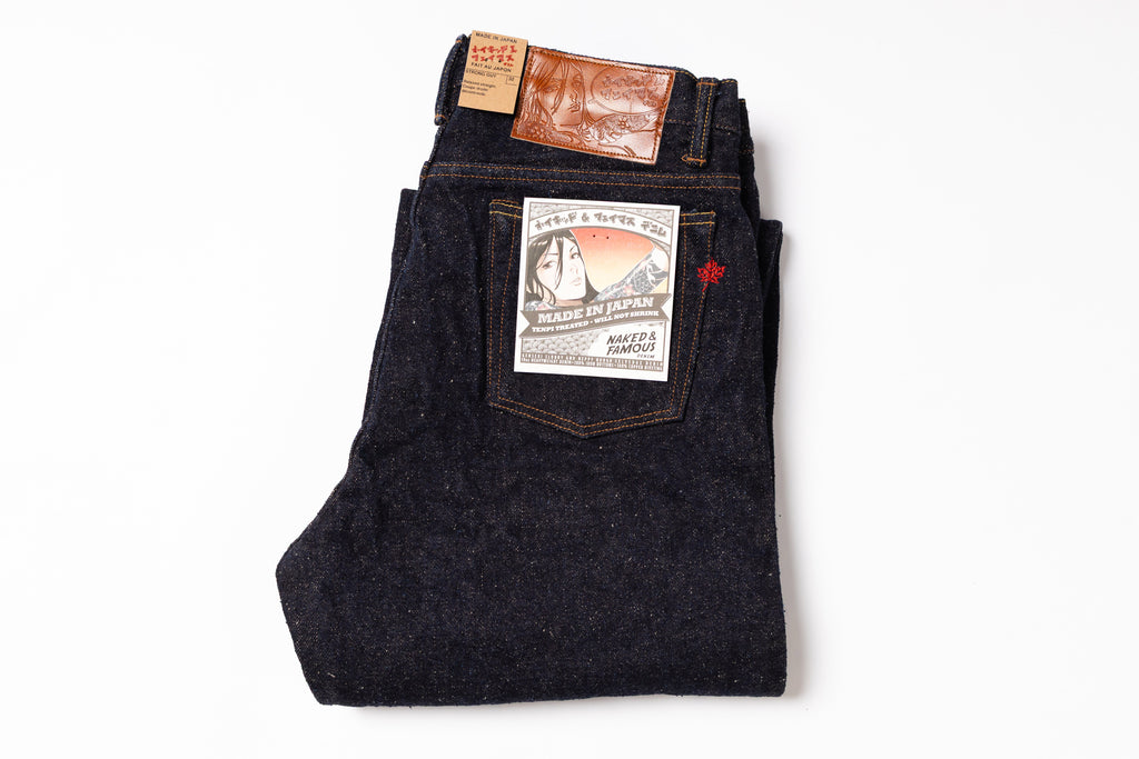 Folded pair of dark blue jeans with a brand label on a white background