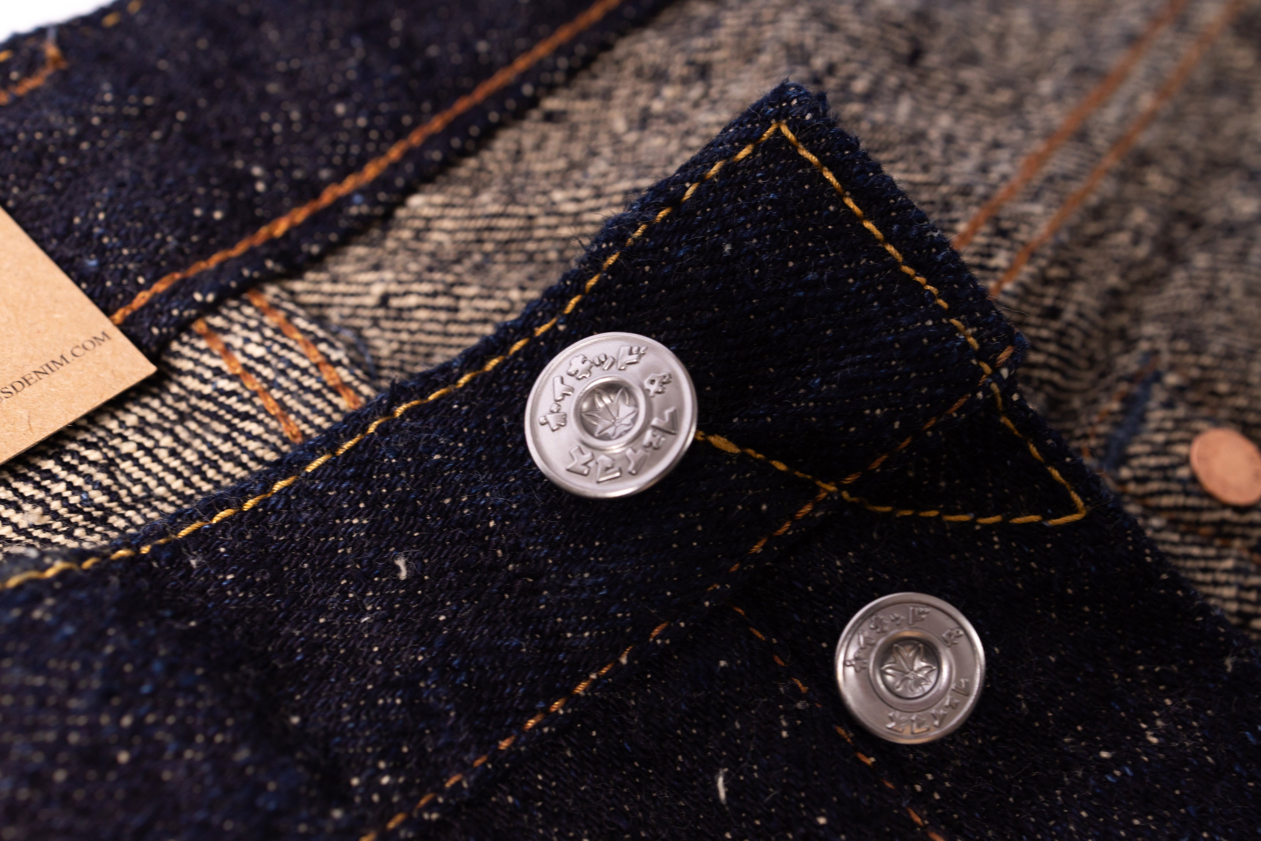 Close-up of a button on a denim jacket with a brand tag.