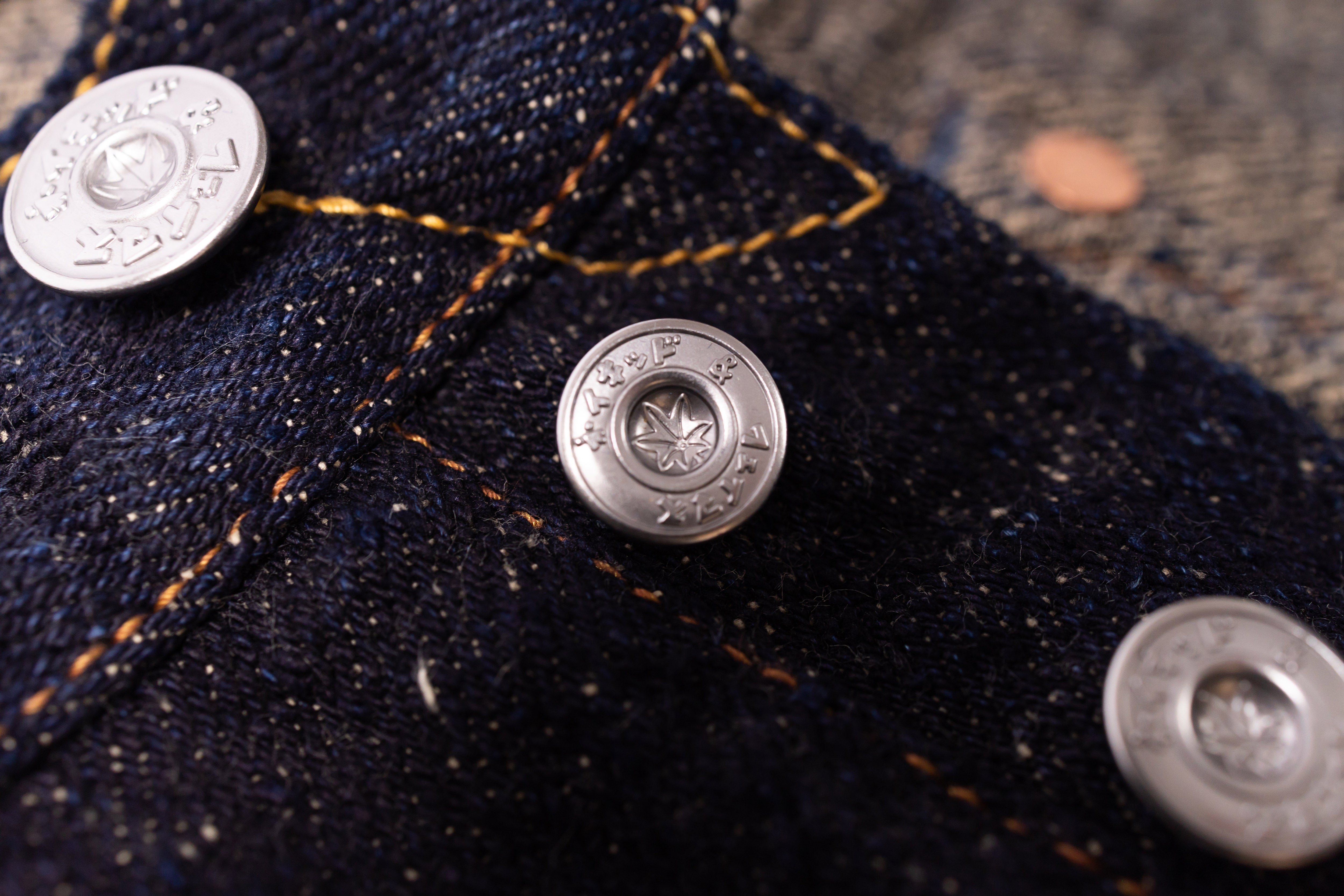 Close-up of denim fabric with metal buttons and stitching details