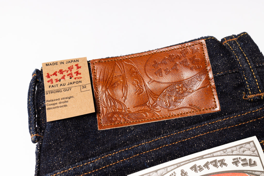 Close-up of a denim product with a brown leather patch and label on a white background