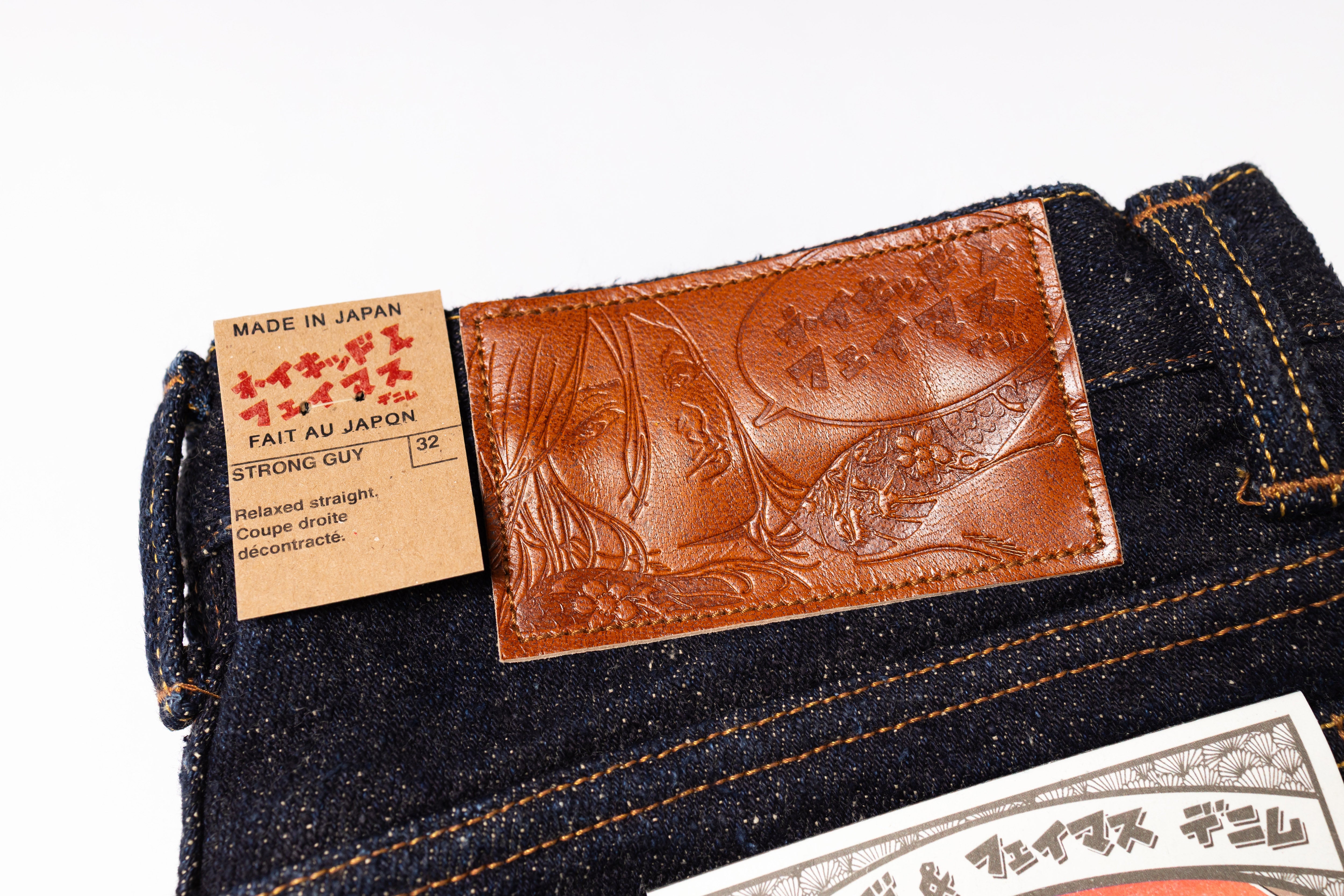 Close-up of a denim product with a brown leather patch and label on a white background