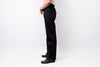 A side profile view of a person wearing black straight-leg jeans, a white shirt, and black leather shoes against a plain white studio background.