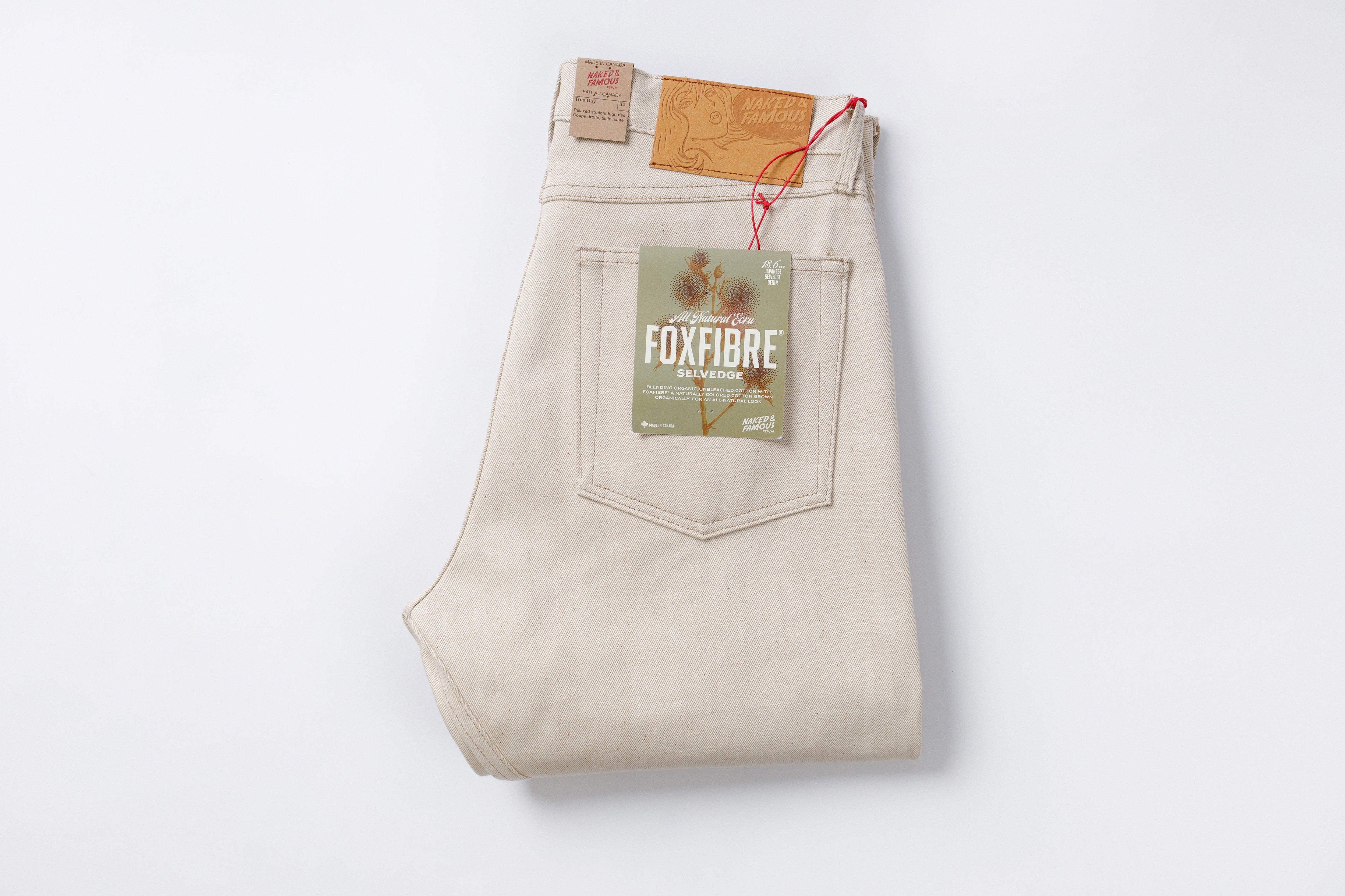 Folded beige jeans with a visible brand label on a white background