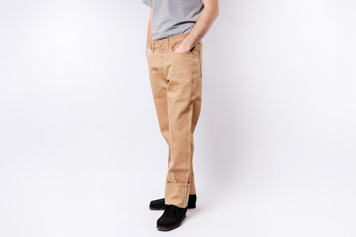Person wearing beige pants and black shoes on a white background