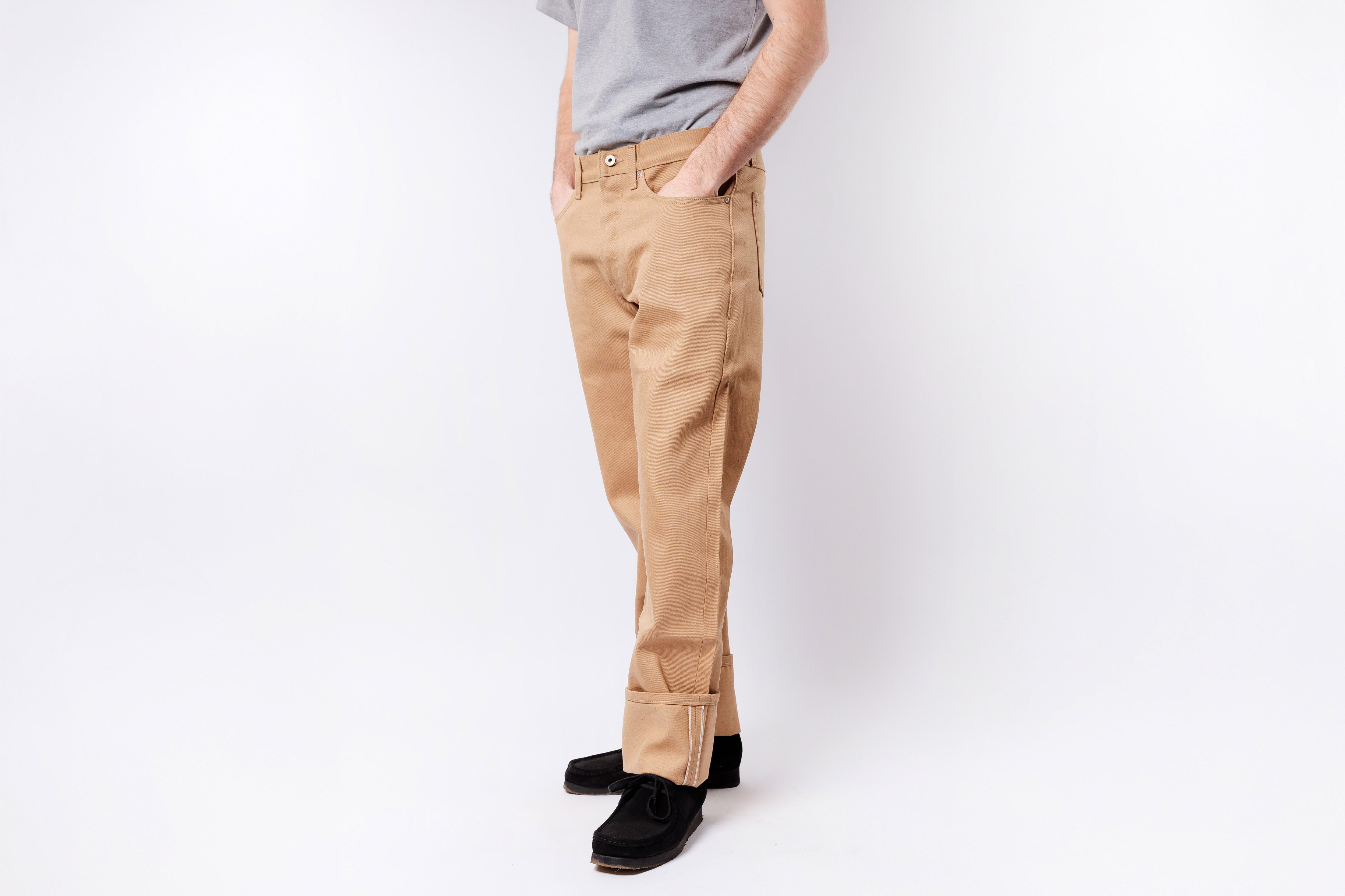 Person wearing beige pants and black shoes on a white background