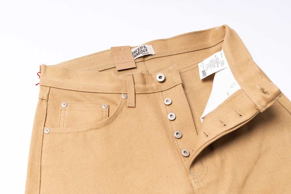 Close-up of beige pants with button details on a white background