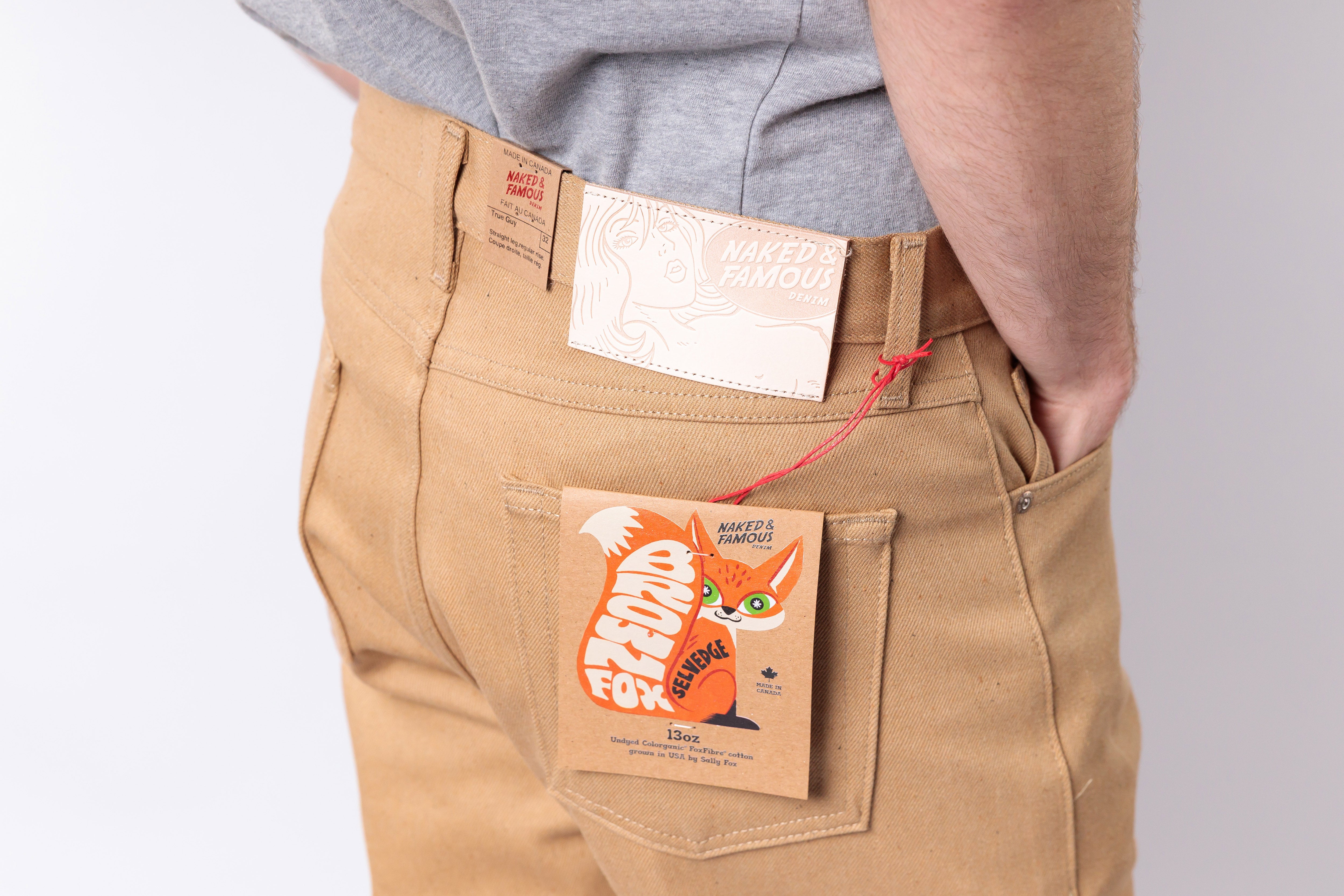 Person wearing beige pants with a brand label and a small pouch on the pocket.