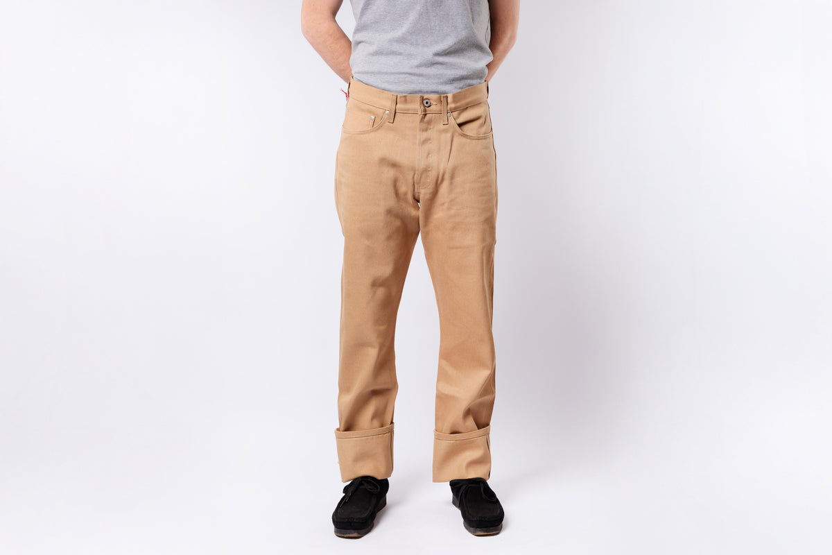 Person wearing beige pants and a gray shirt on a white background