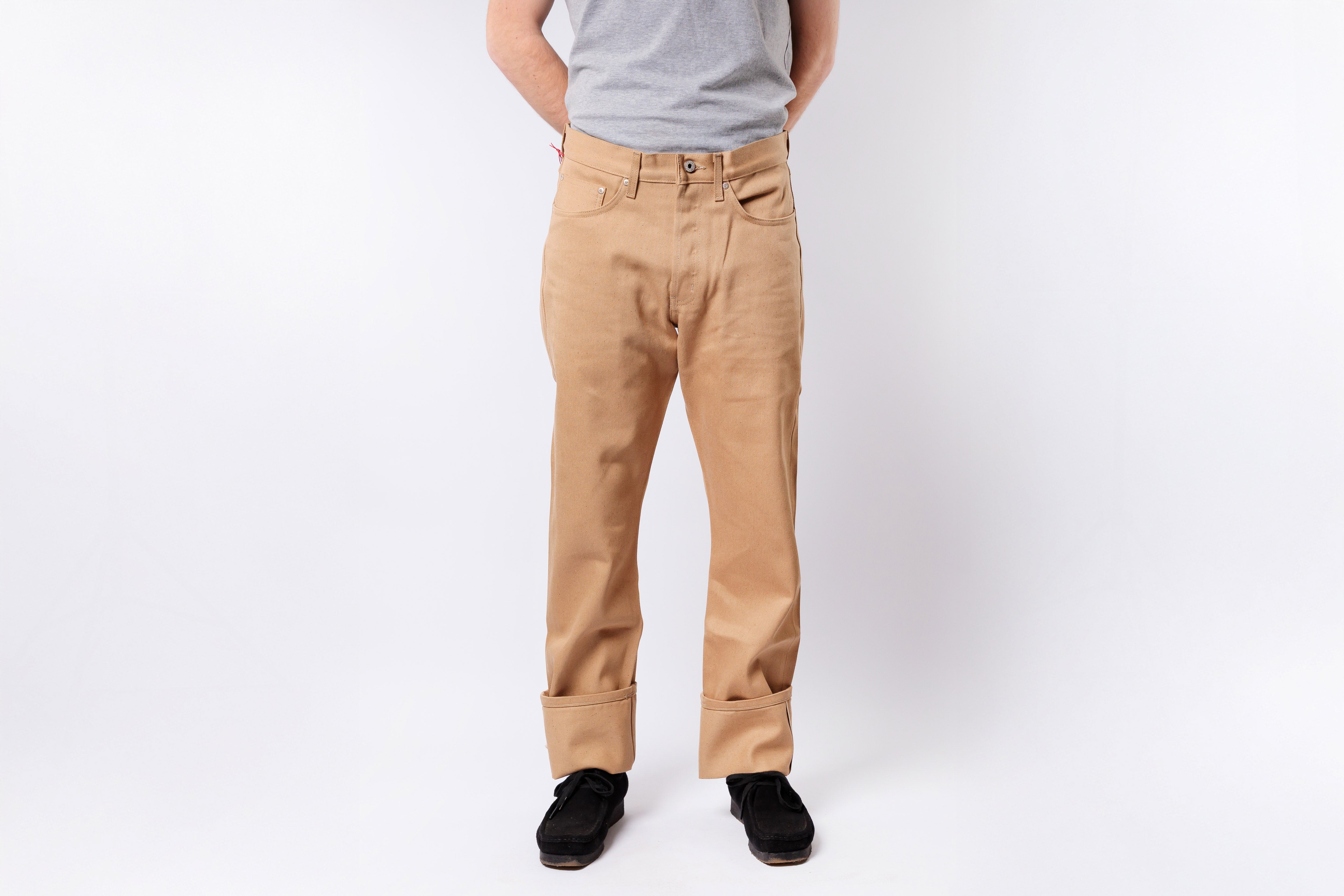 Person wearing beige pants and a gray shirt on a white background