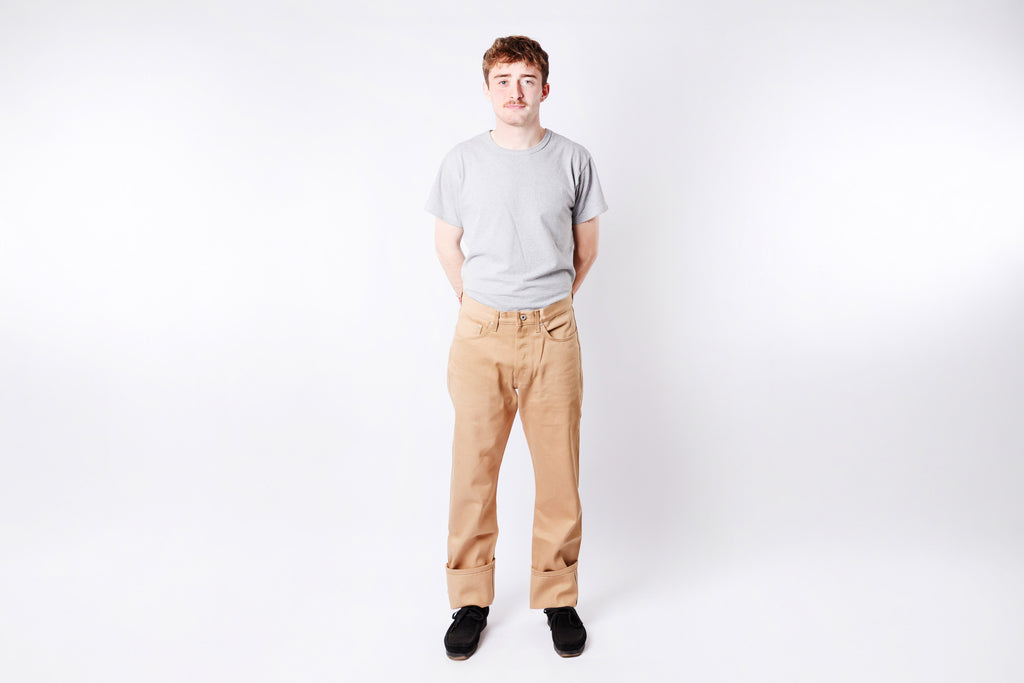 Person wearing a gray t-shirt and beige pants on a white background