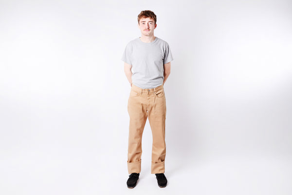 Person wearing a gray t-shirt and beige pants on a white background