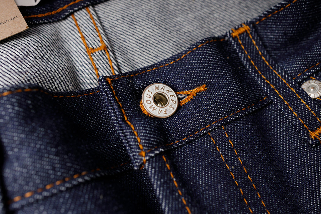 Close-up of a button on a denim fabric with brand name visible