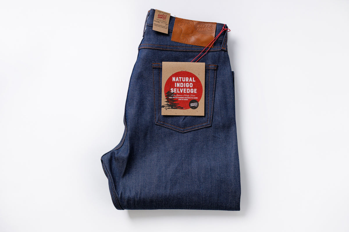 Folded blue denim jeans with a brand label on a white background