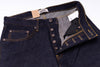 Close-up of dark blue jeans with visible stitching and a brand label on a white background