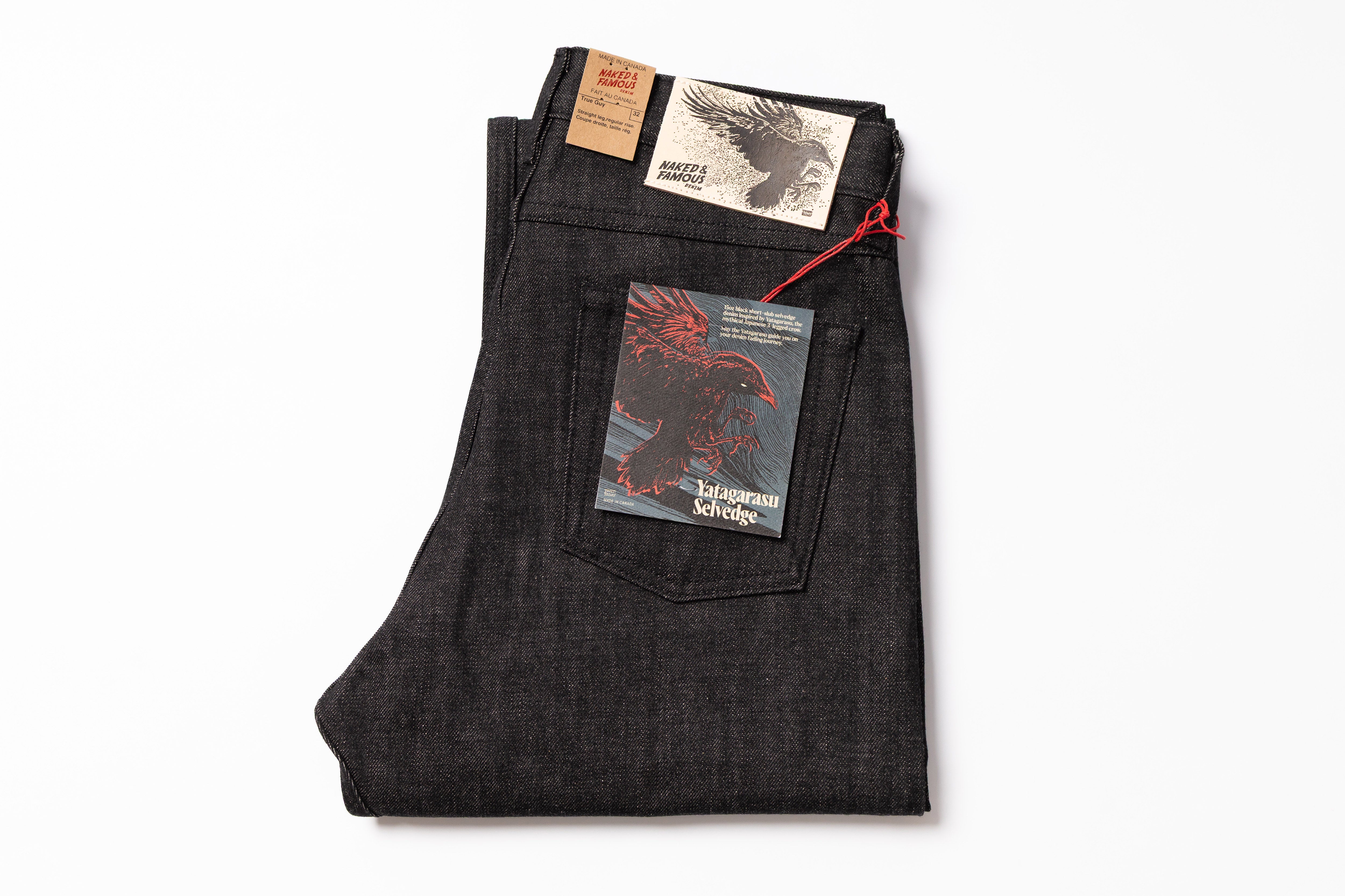 Folded dark denim jeans with labels on a white background