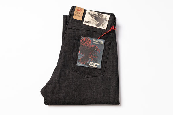 Folded dark denim jeans with labels on a white background