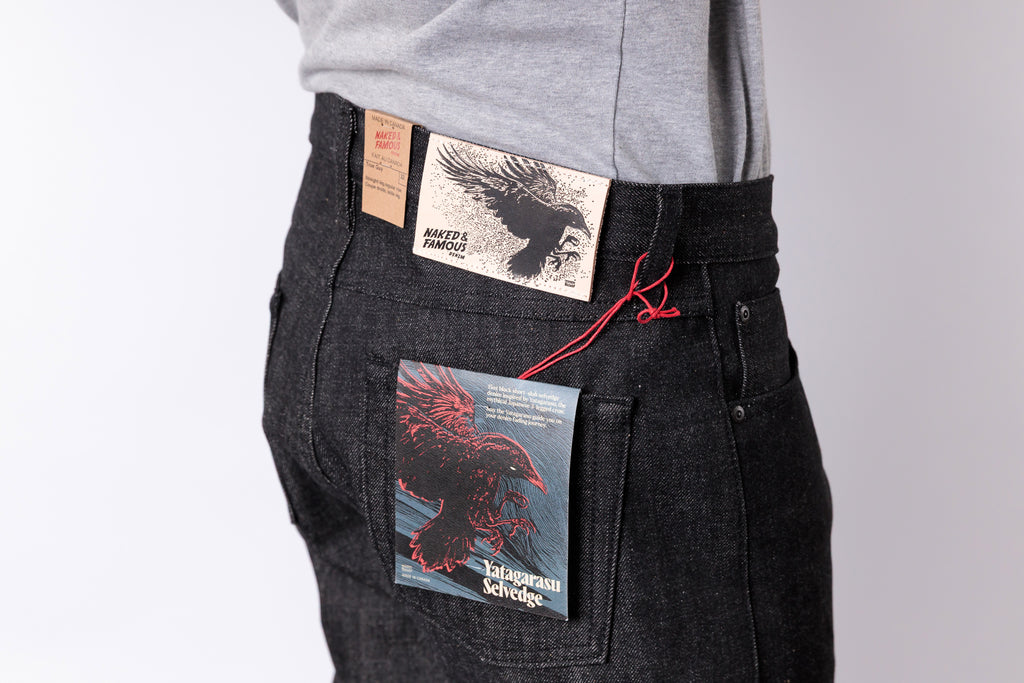 Person wearing black pants with printed labels on a gray background