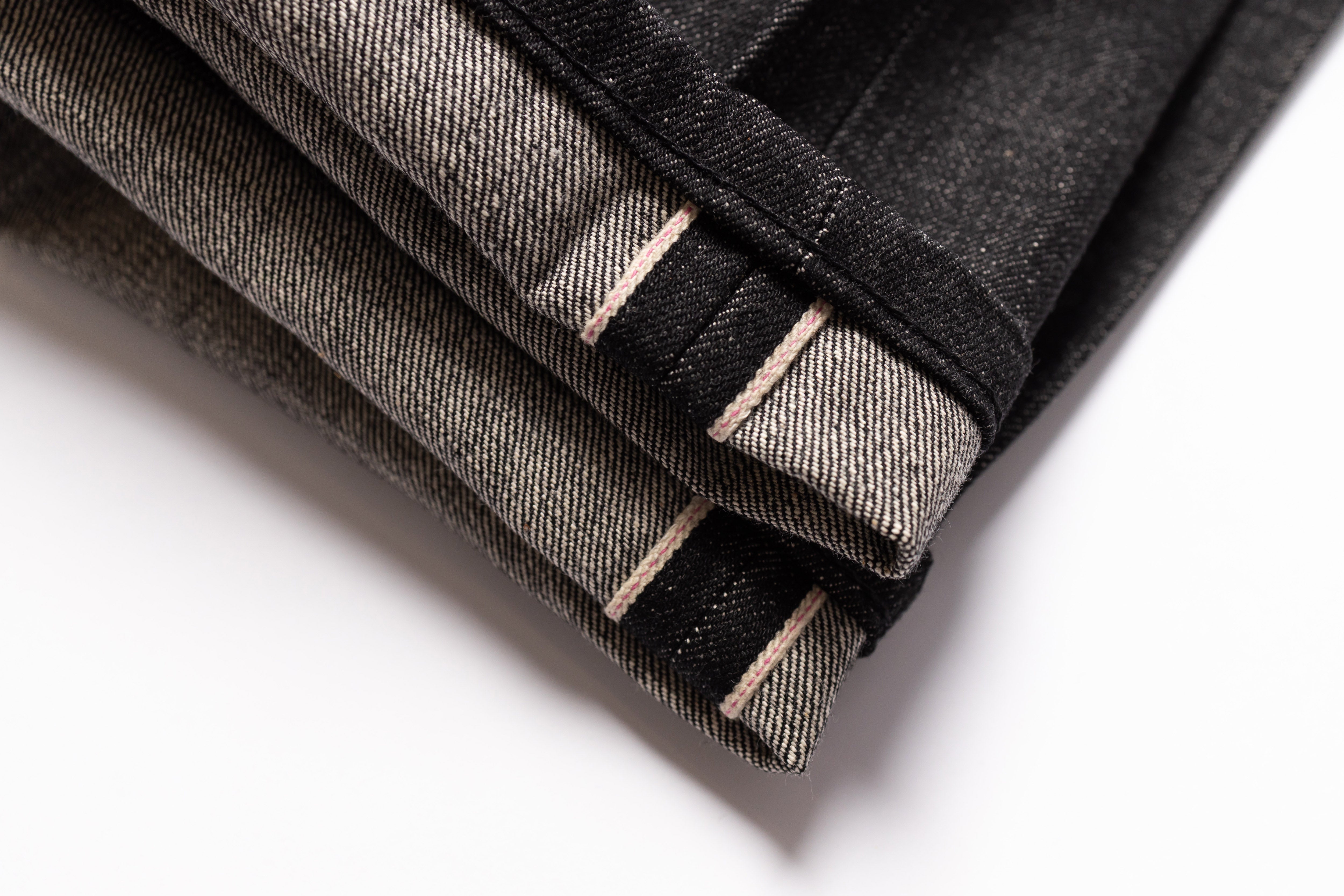 Folded black denim jeans on a white background