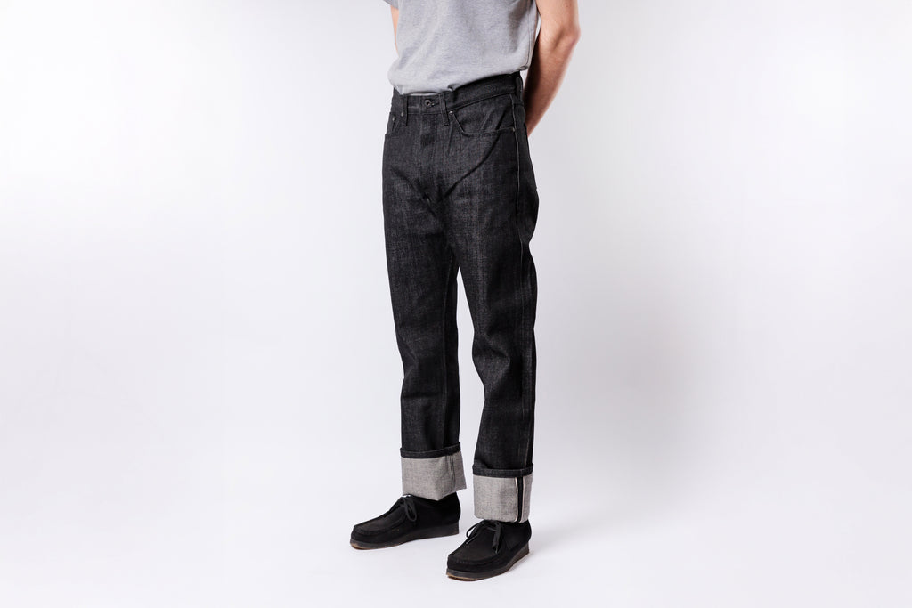 Person wearing black jeans and a gray shirt on a white background