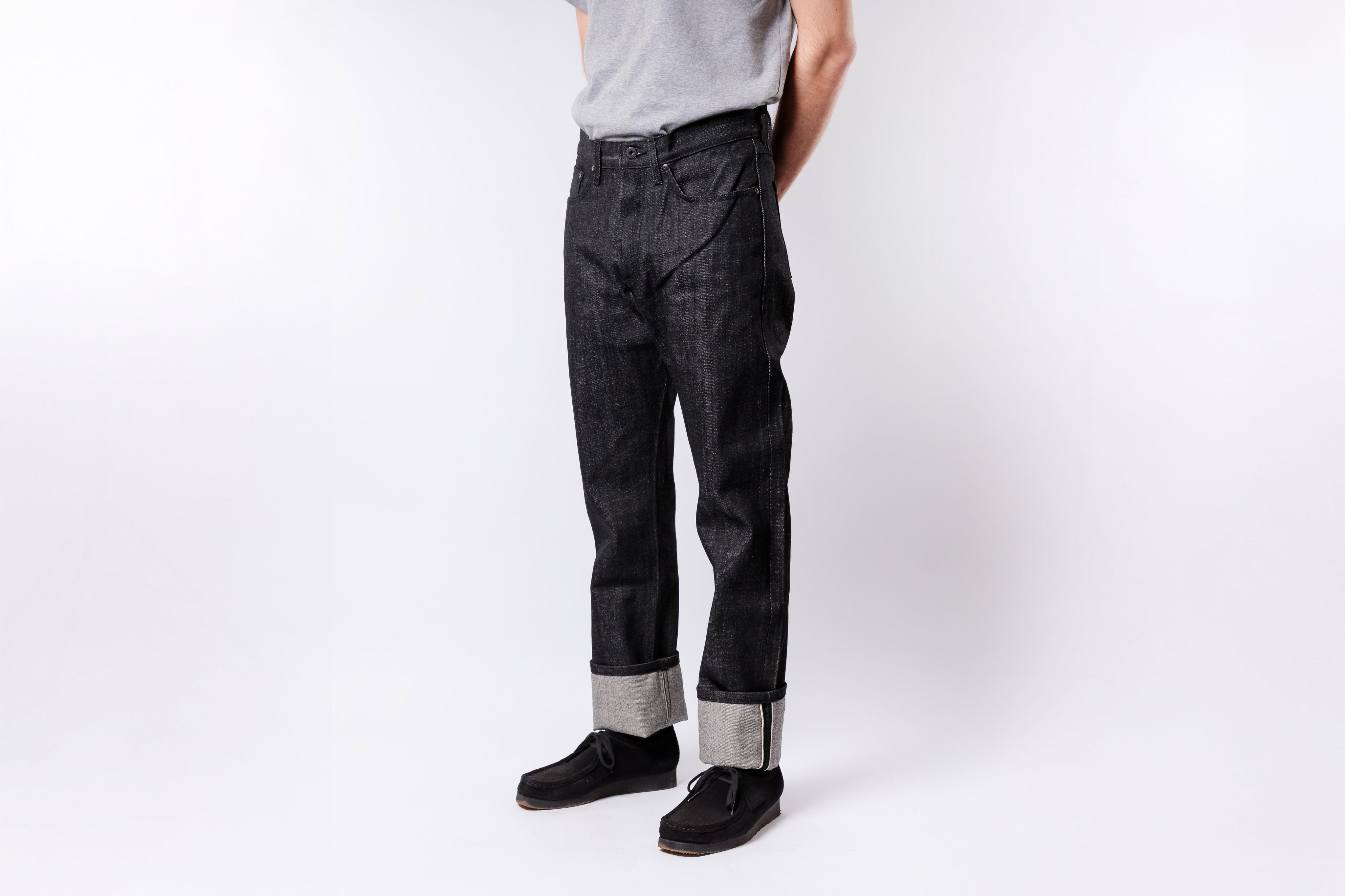 Person wearing black jeans and a gray shirt on a white background