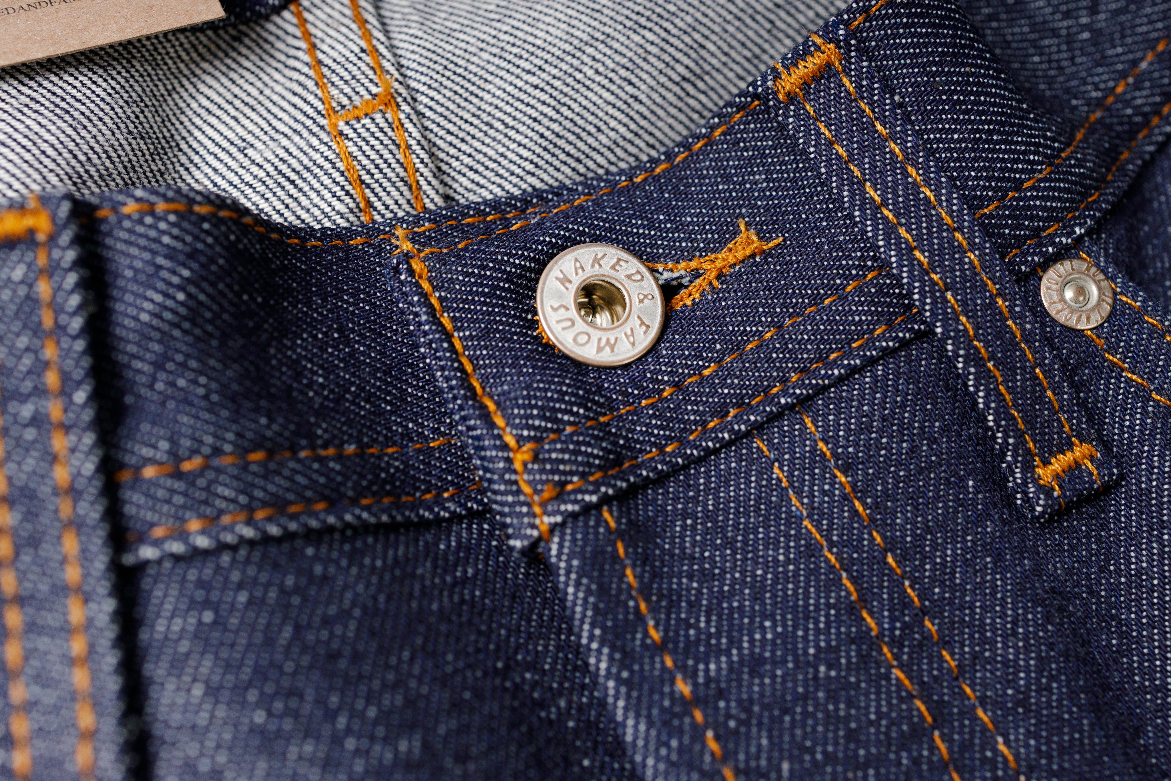 Close-up of blue denim fabric with a button and stitching details