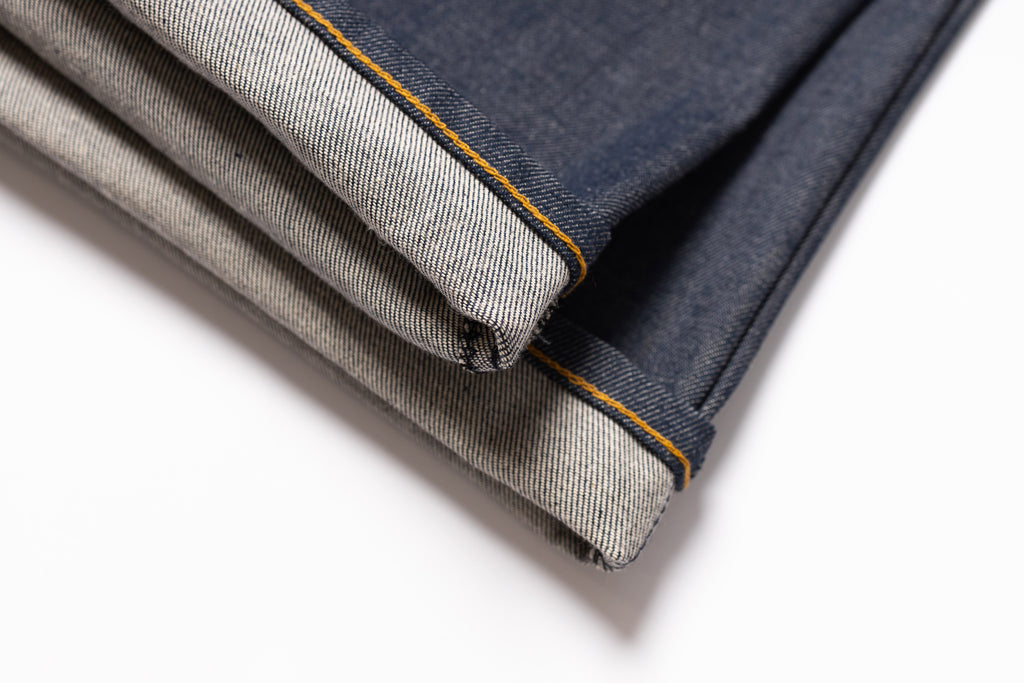 Two pairs of jeans, one dark blue and one gray, folded and placed on a white background.