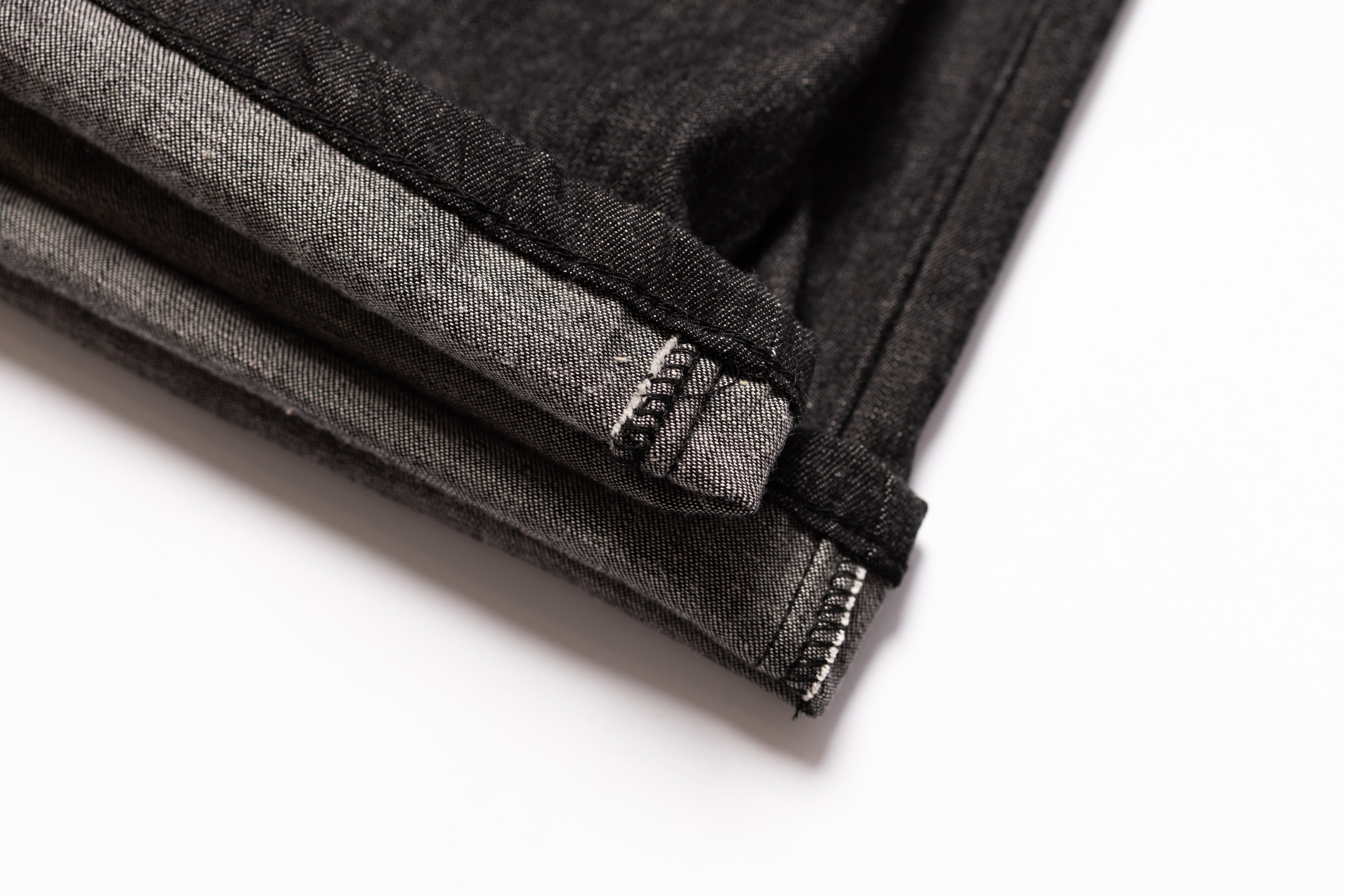 Close-up of black denim fabric with a brand label on a white background