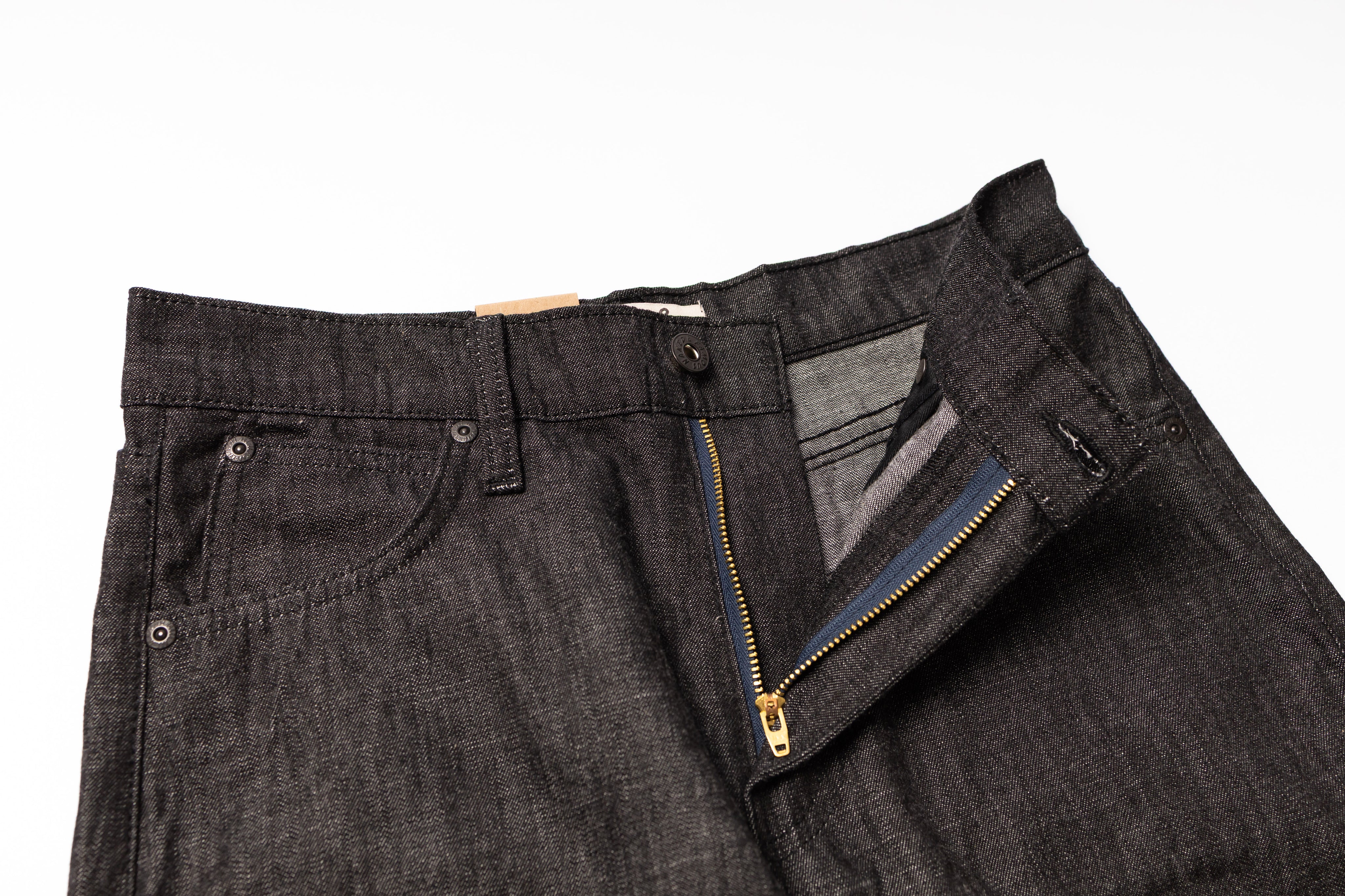 Close-up of dark gray jeans with a zipper detail on a white background