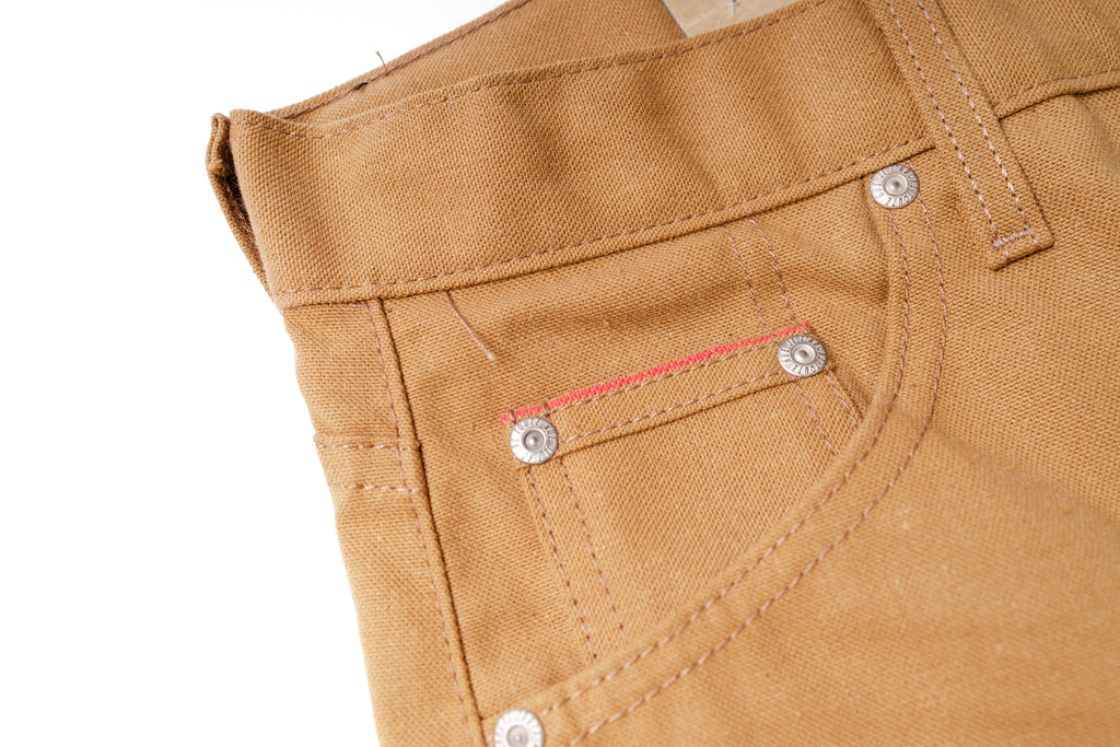 Close-up of brown pants with stitching details on a white background