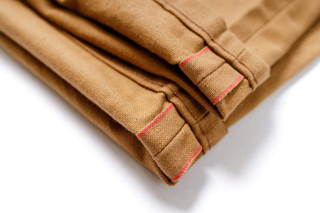 Folded brown fabric with red stitching on a white background