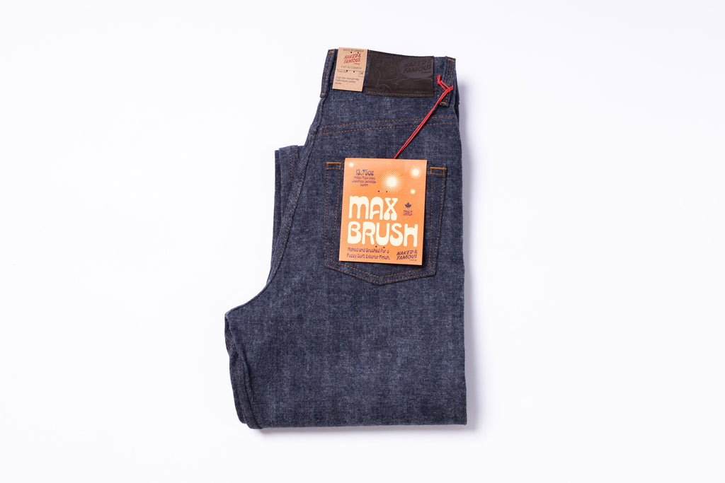 Folded blue denim jeans with a 'Max Brush' label on a white background