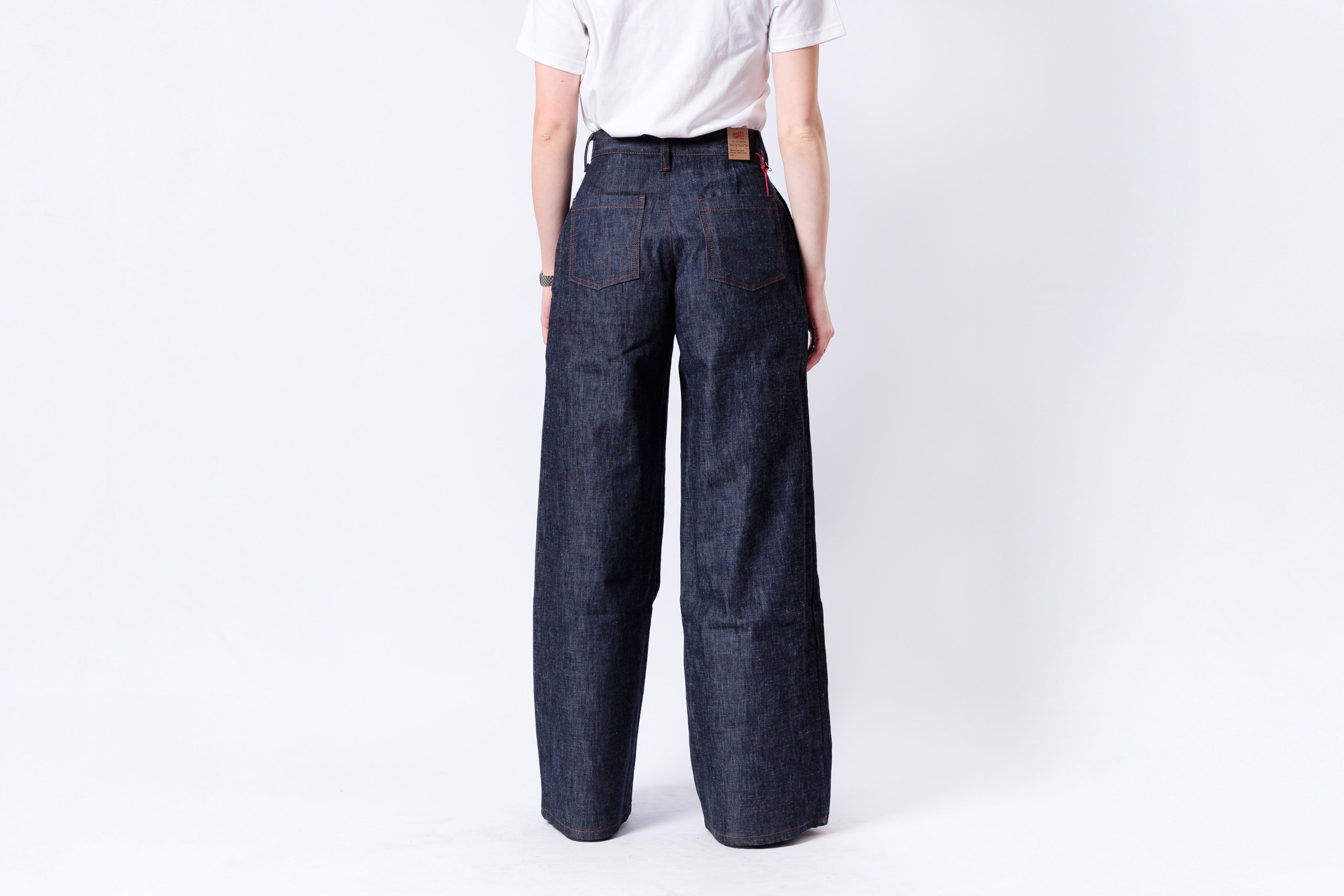 Person wearing dark blue wide-leg jeans on a white background