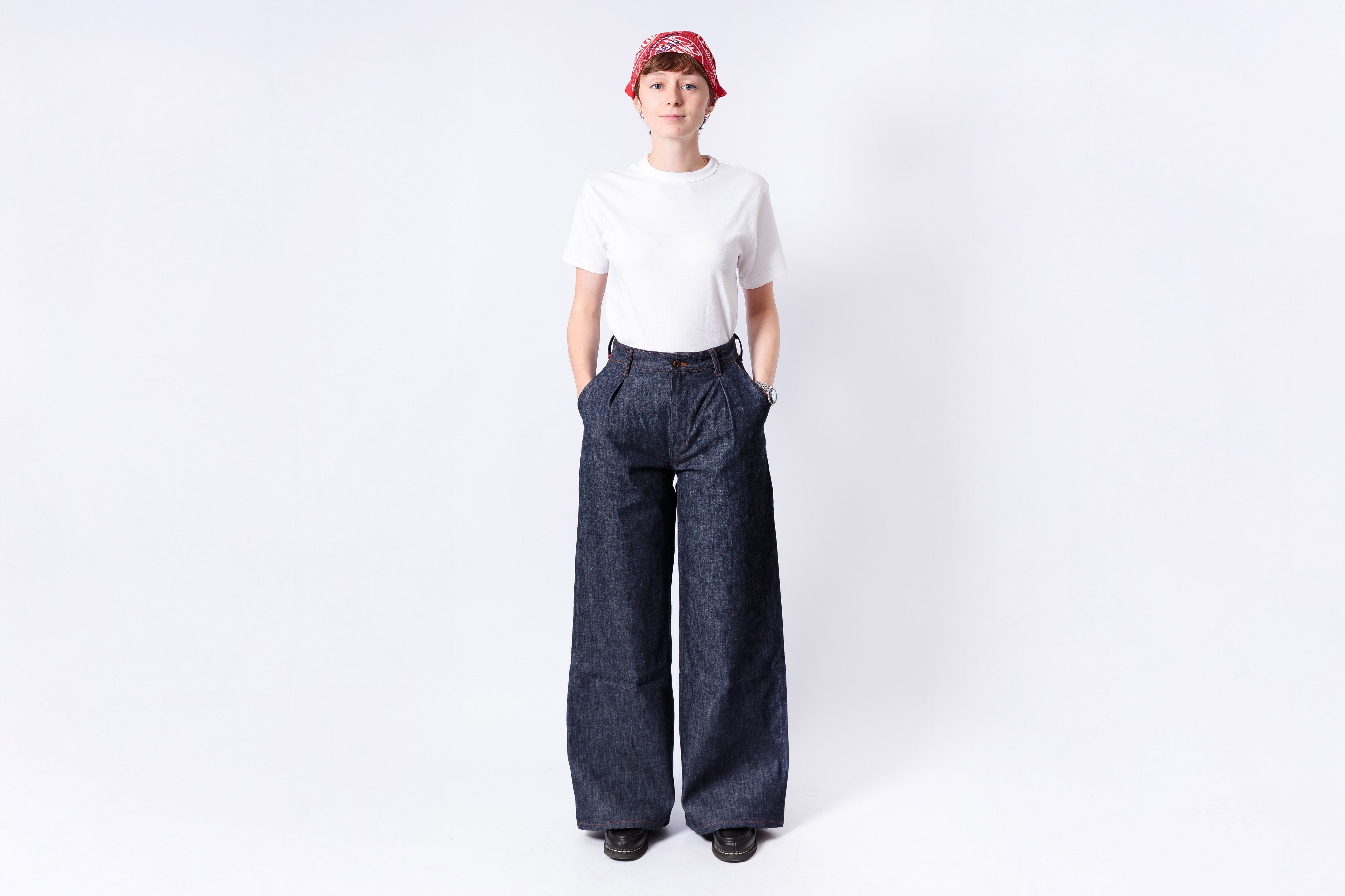 Person wearing a white shirt and dark blue wide-leg pants on a white background