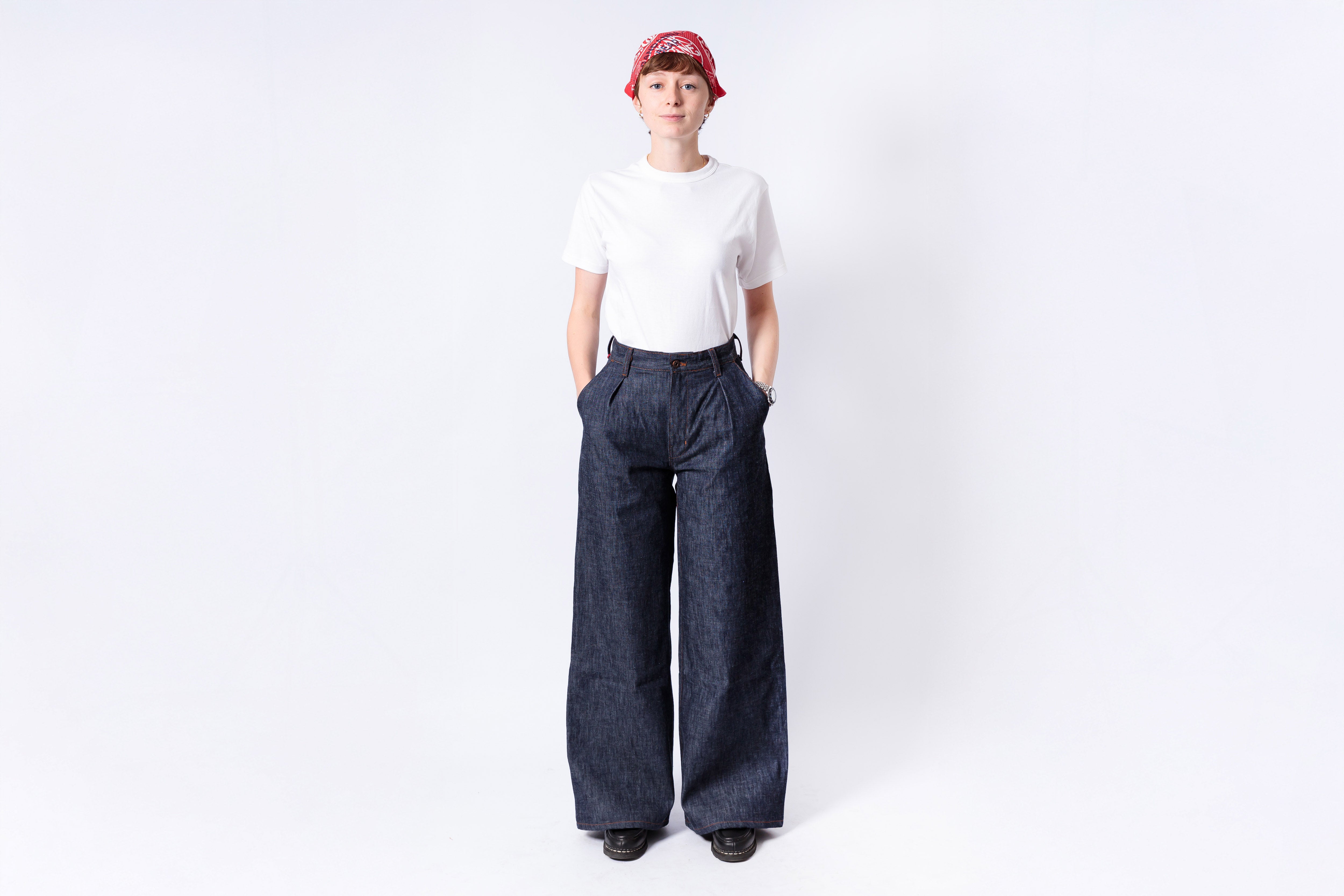 Person wearing a white shirt and dark blue wide-leg pants on a white background