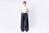 Person wearing a white shirt and dark blue wide-leg pants on a white background