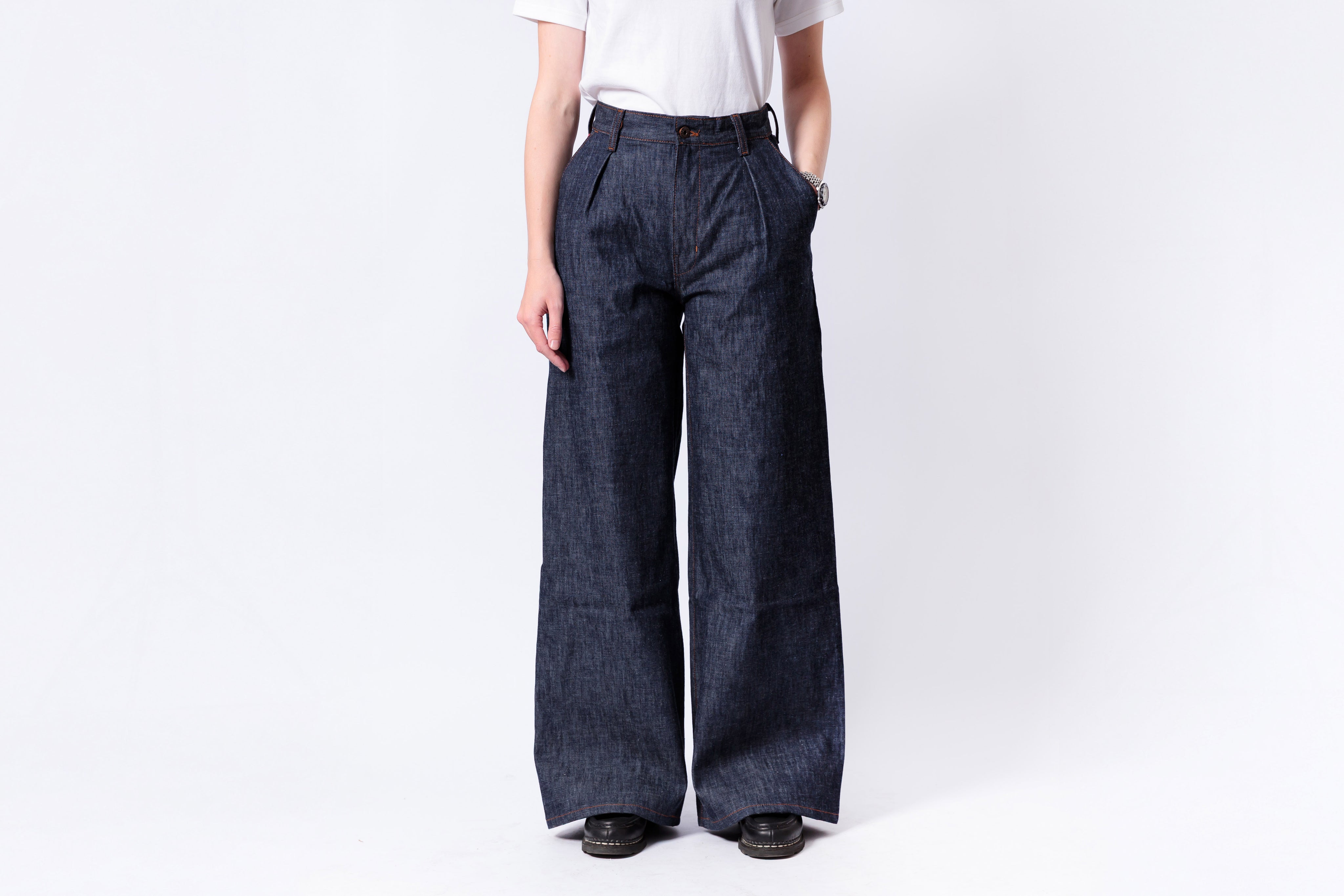 Person wearing dark blue wide-leg jeans on a white background