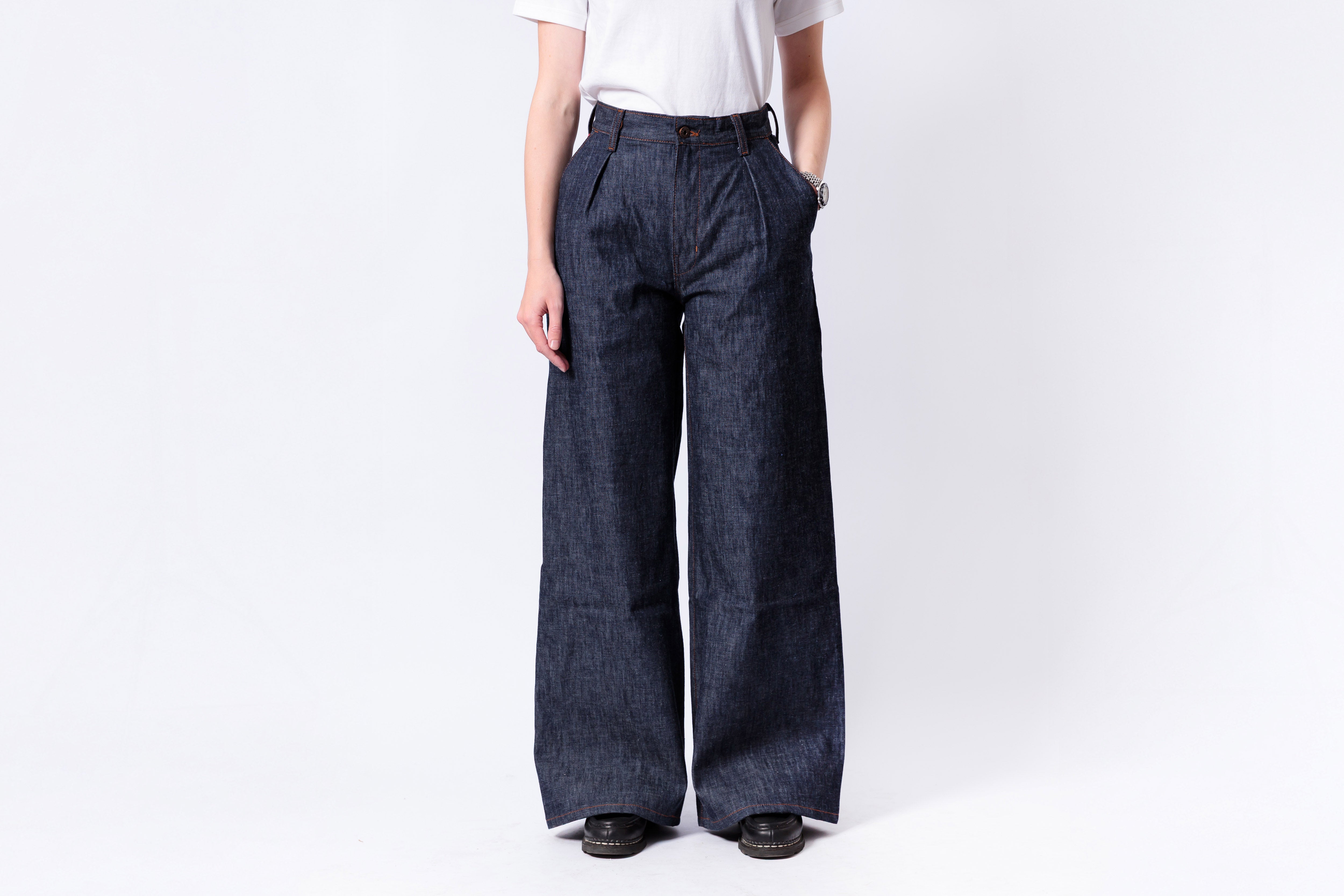 Person wearing dark blue wide-leg jeans on a white background