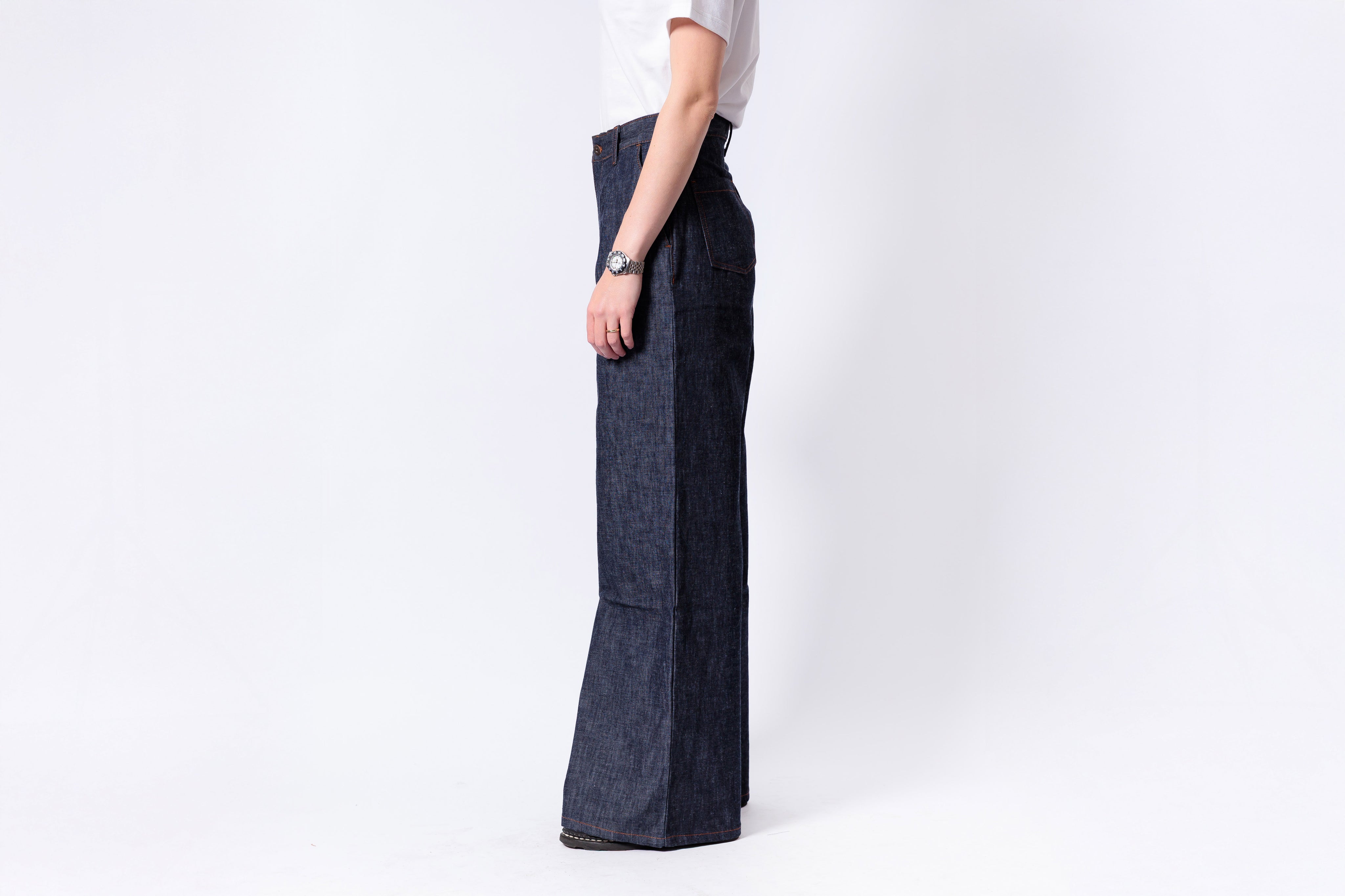 Person wearing dark denim wide-leg pants on a white background