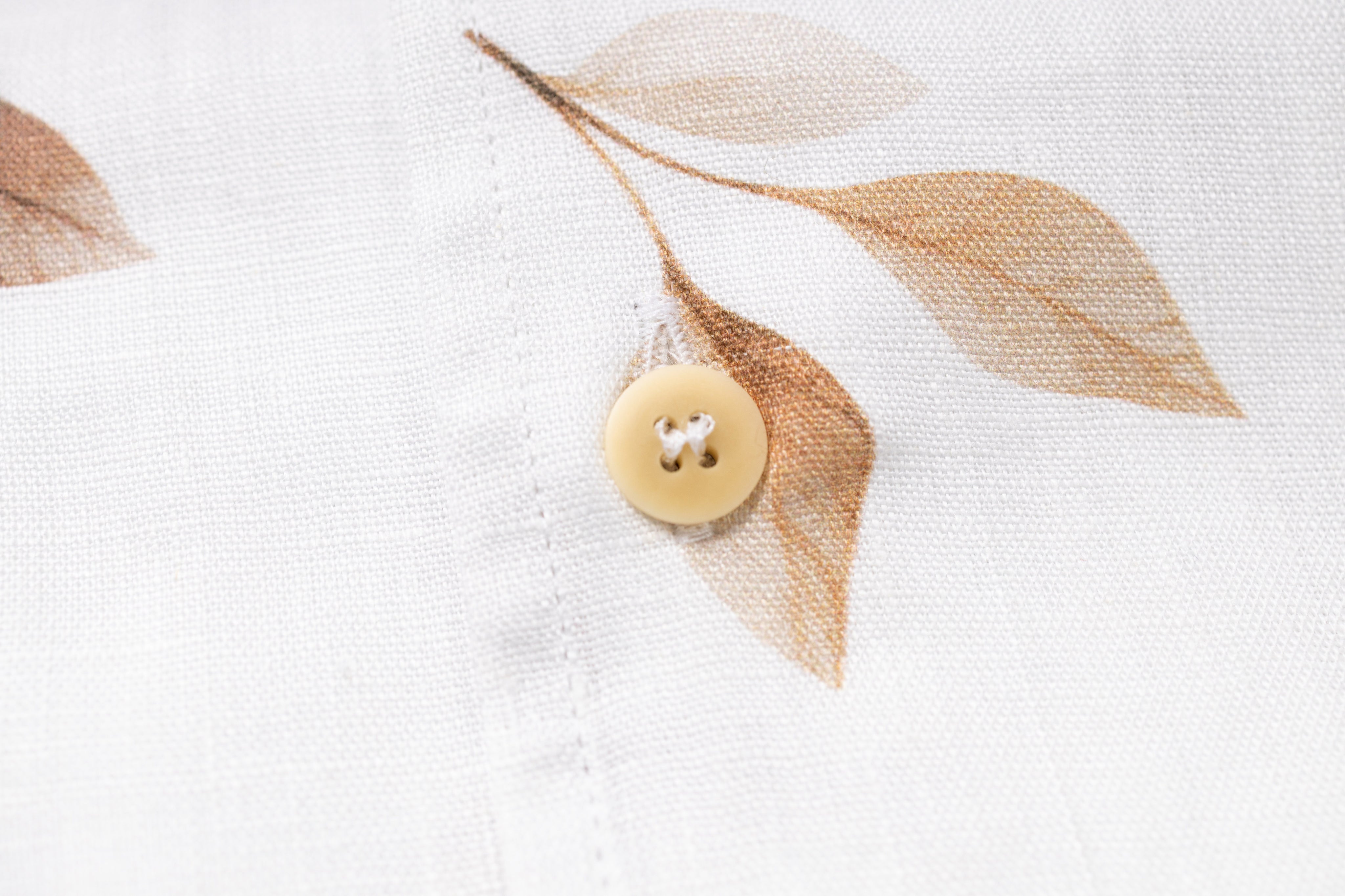 Close-up of a button and leaves on a textured white surface