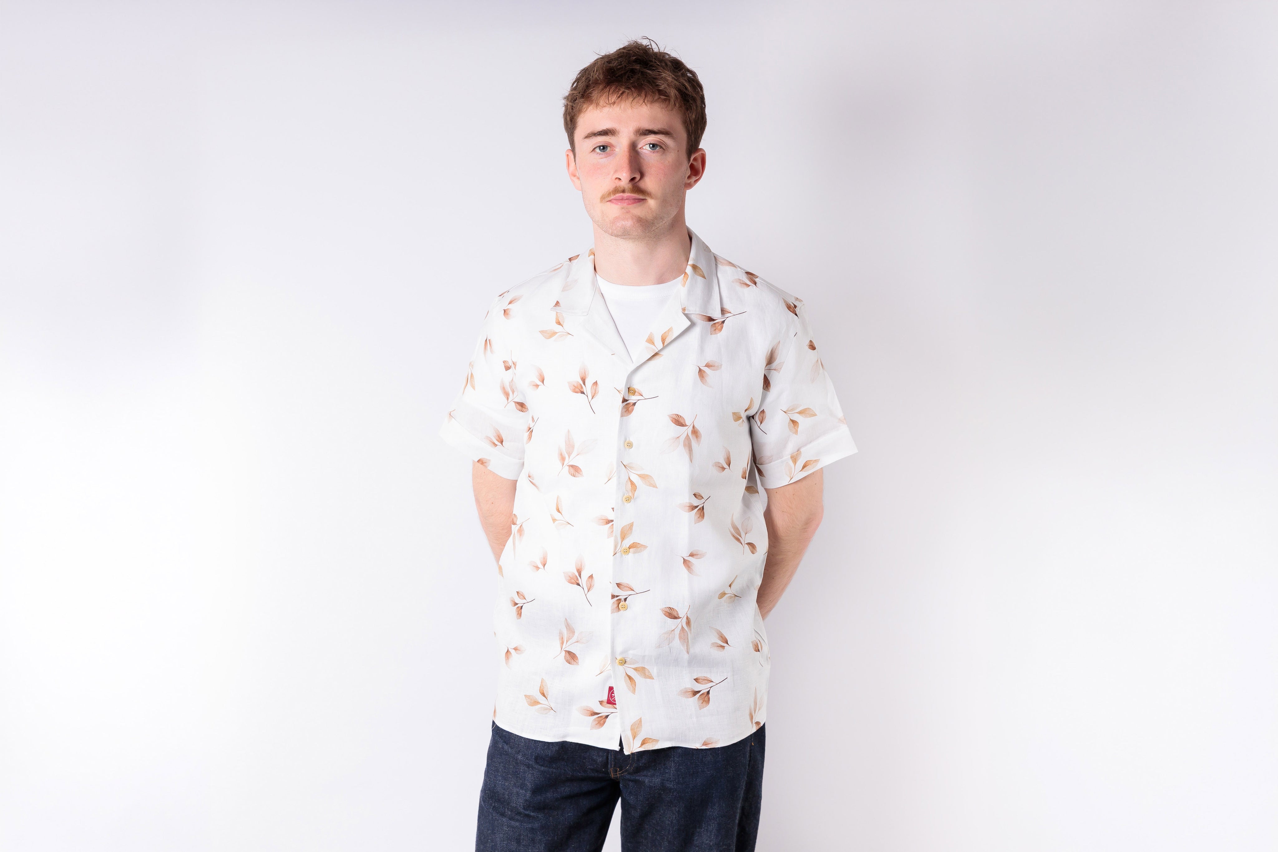 Man wearing a white floral shirt against a plain background
