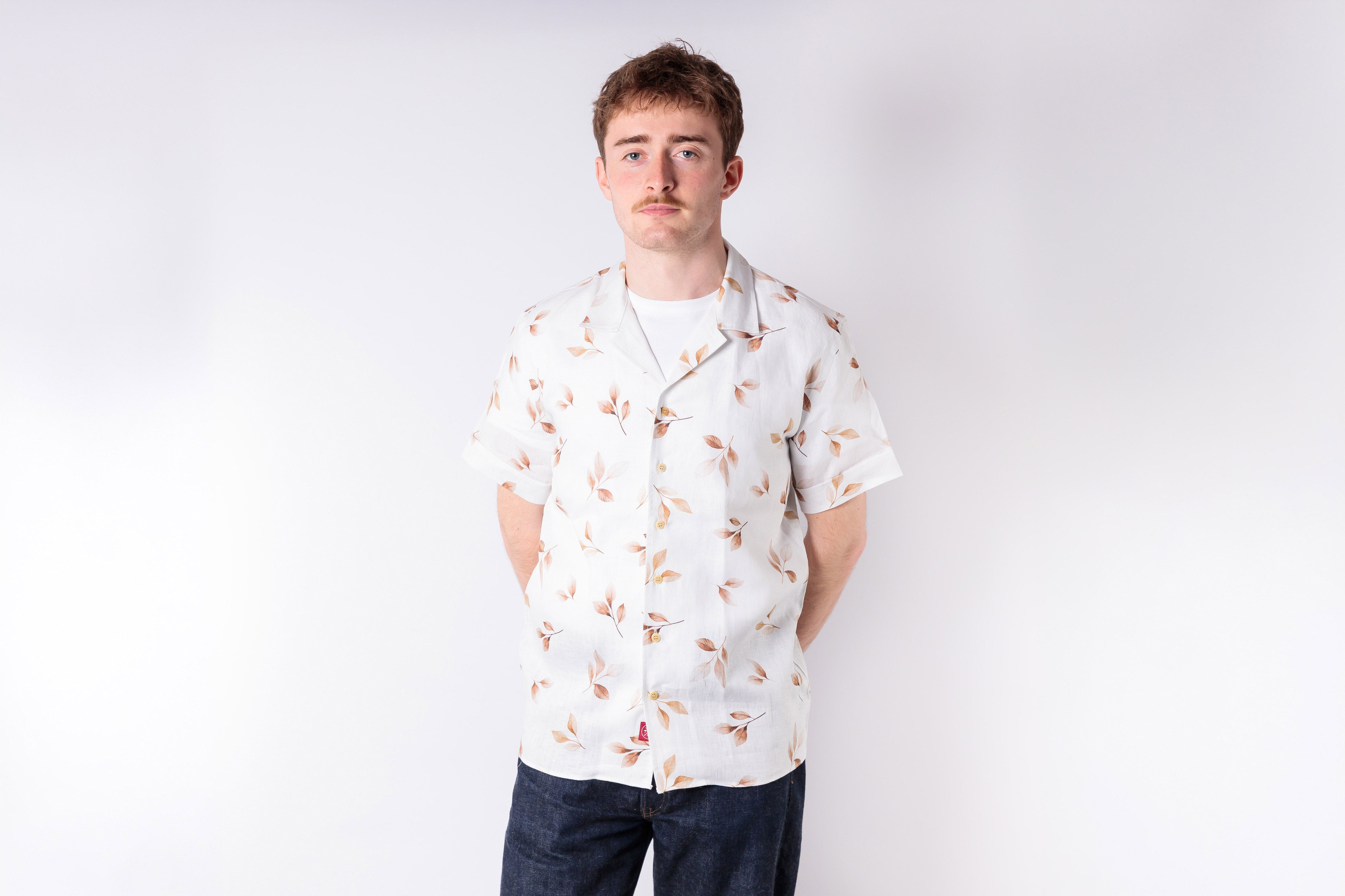Man wearing a white floral shirt against a plain background