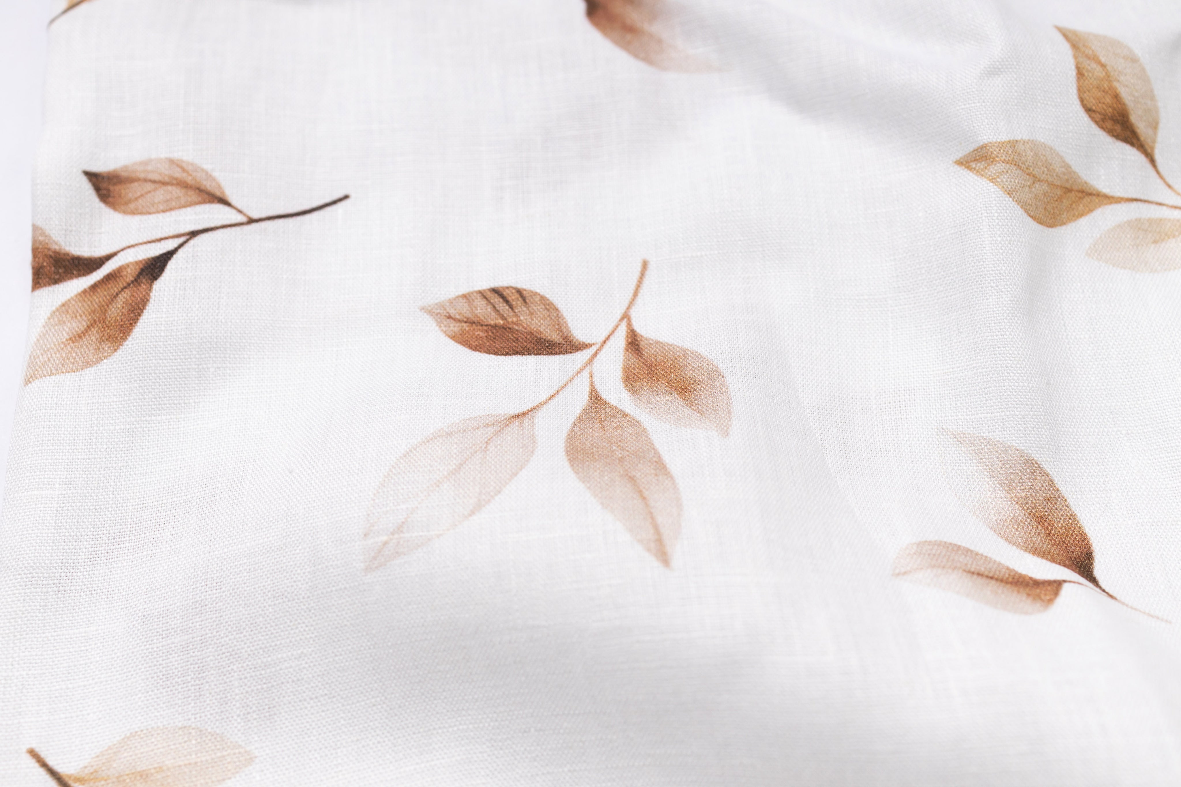 Close-up of fabric with brown leaf pattern on a white background