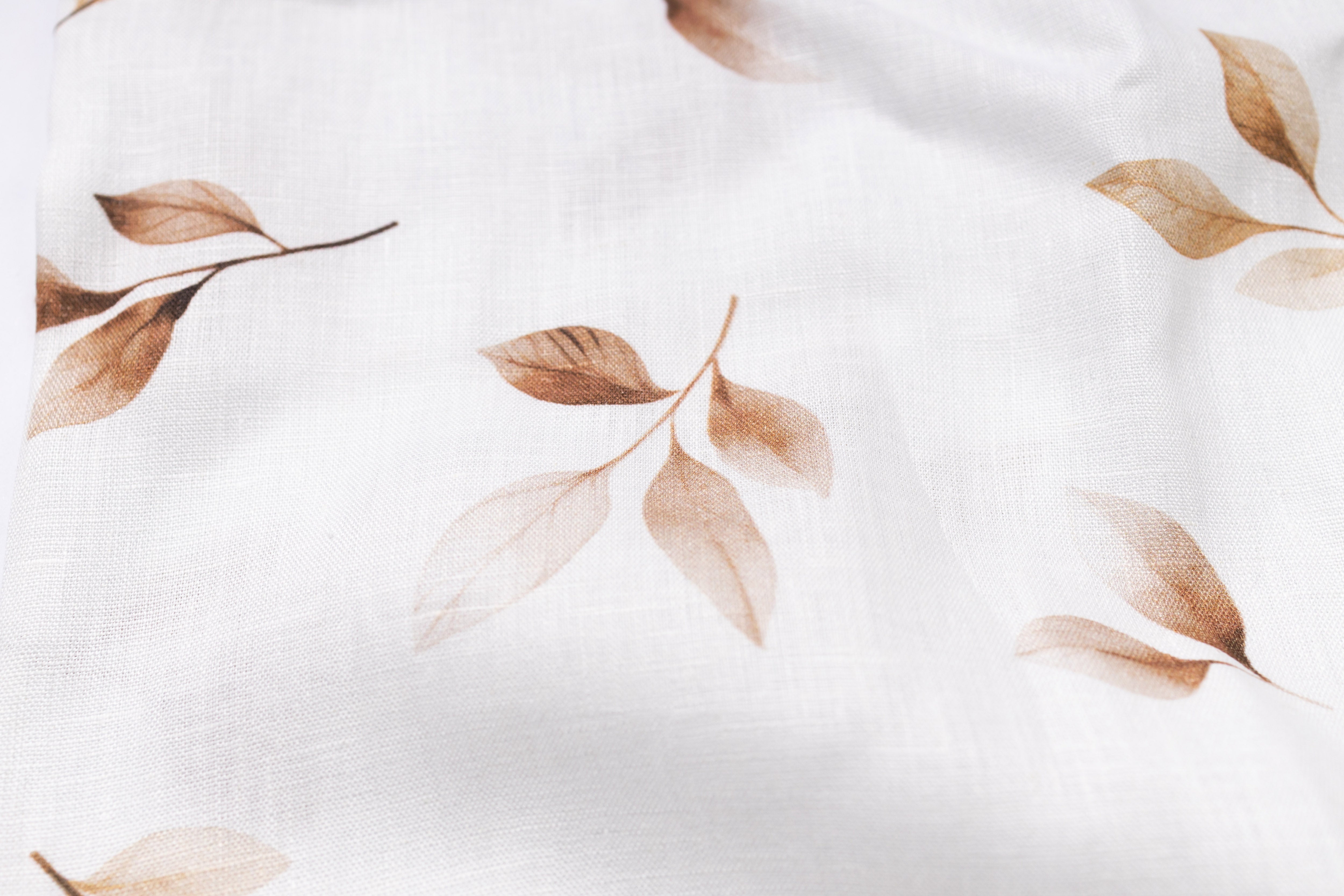 Close-up of fabric with brown leaf pattern on a white background
