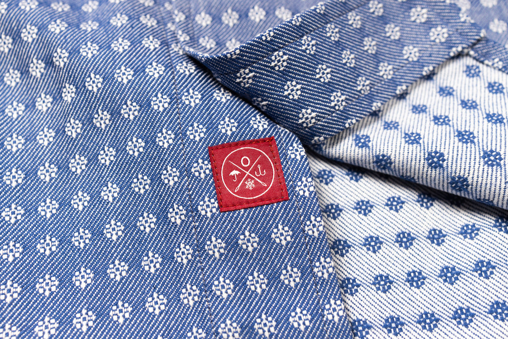 Blue fabric with white floral pattern and a red label featuring a mountain design.
