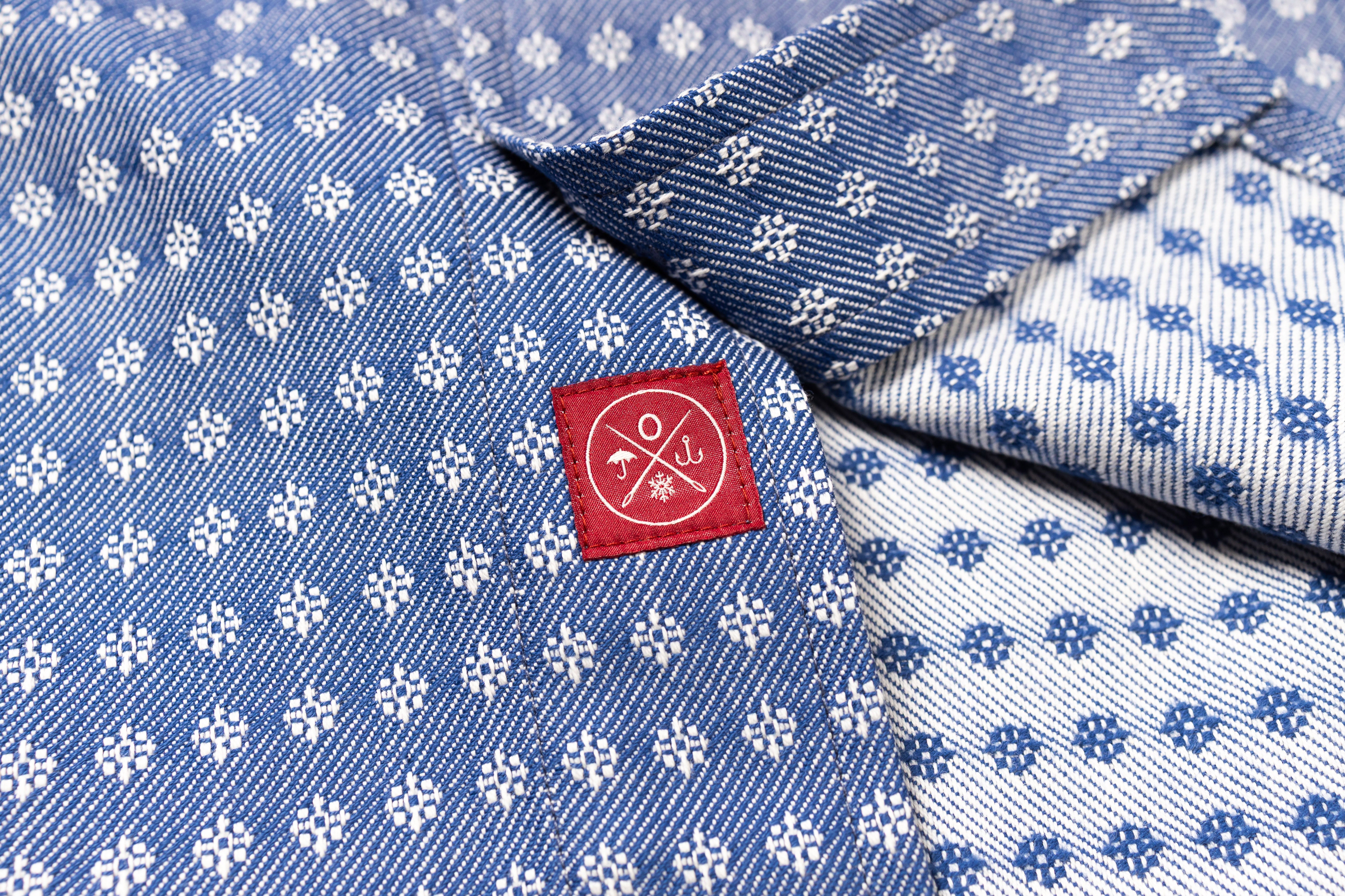 Blue fabric with white floral pattern and a red label featuring a mountain design.