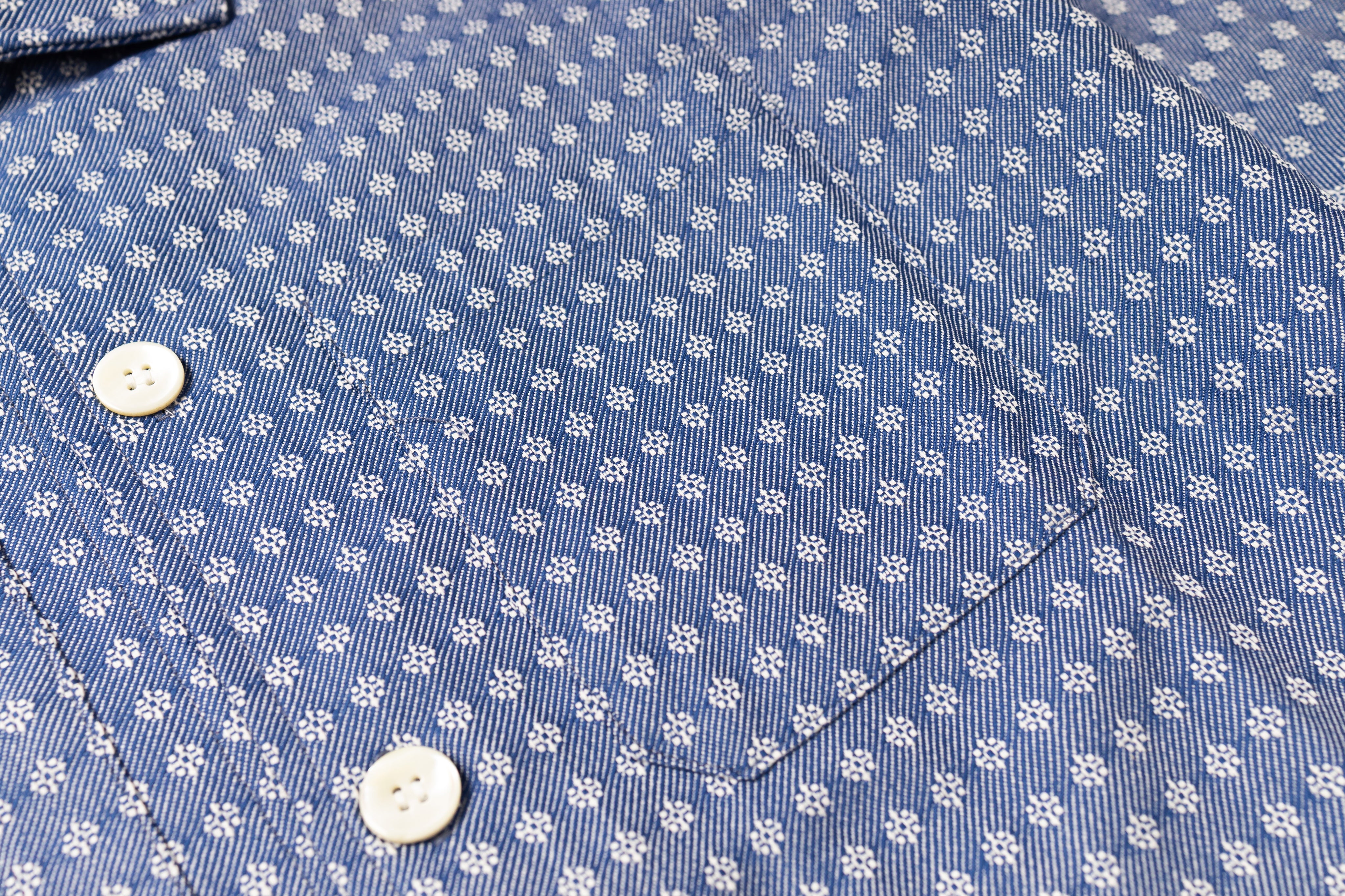 Close-up of a blue shirt with white floral pattern and buttons.