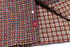 Close-up of patterned fabric with a button and brand logo.