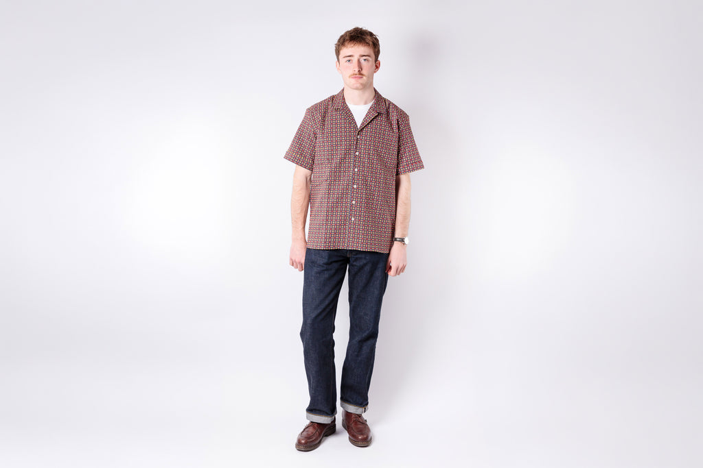 Man wearing a checkered shirt and jeans on a white background
