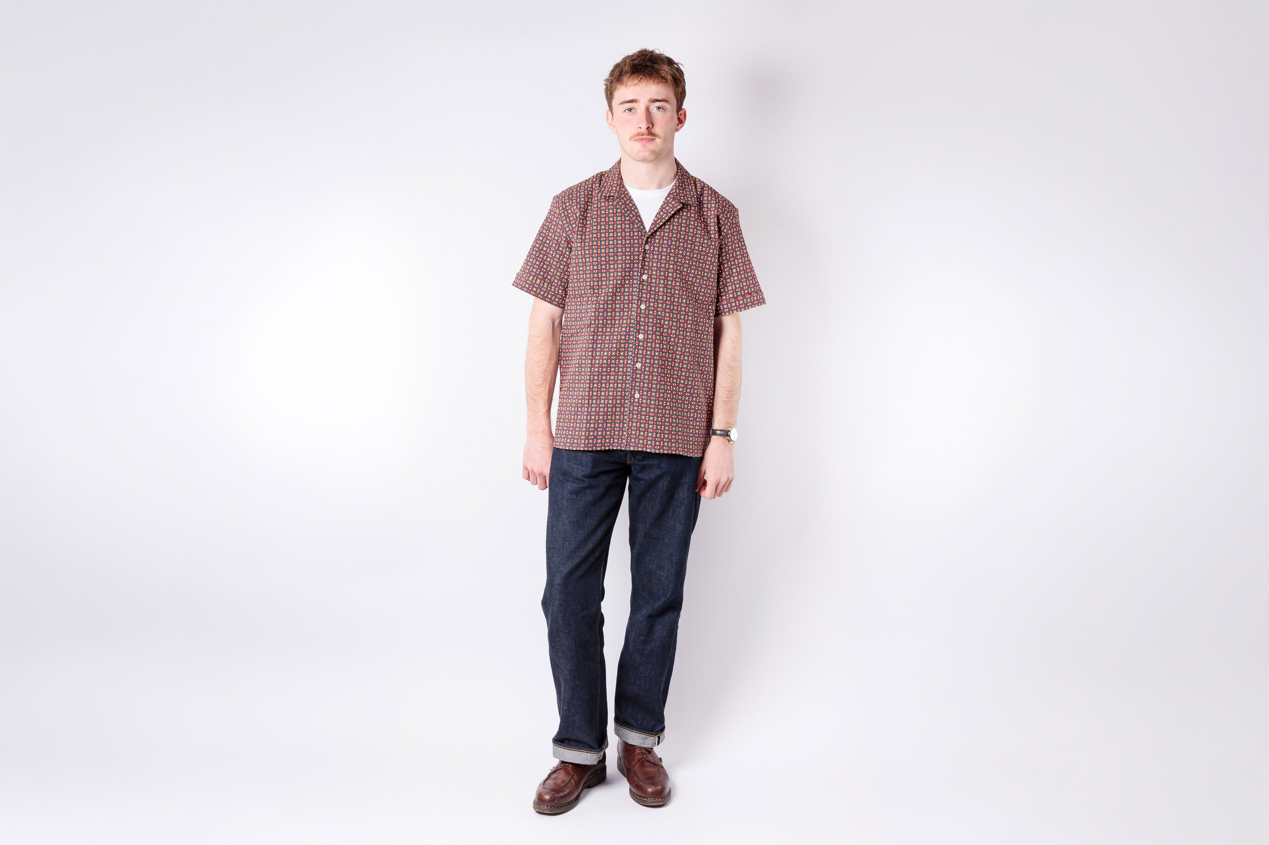 Man wearing a checkered shirt and jeans on a white background