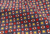 Close-up of patterned fabric with red, yellow, and white designs on a dark background